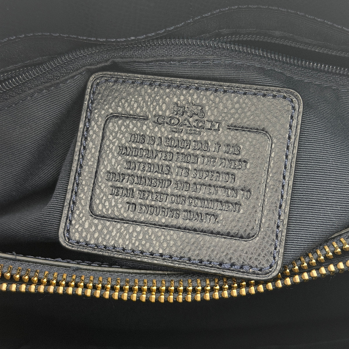 Coach Minetta Satchel in navy blue grained leather with dual handles and detachable shoulder strap displayed on a white background.
