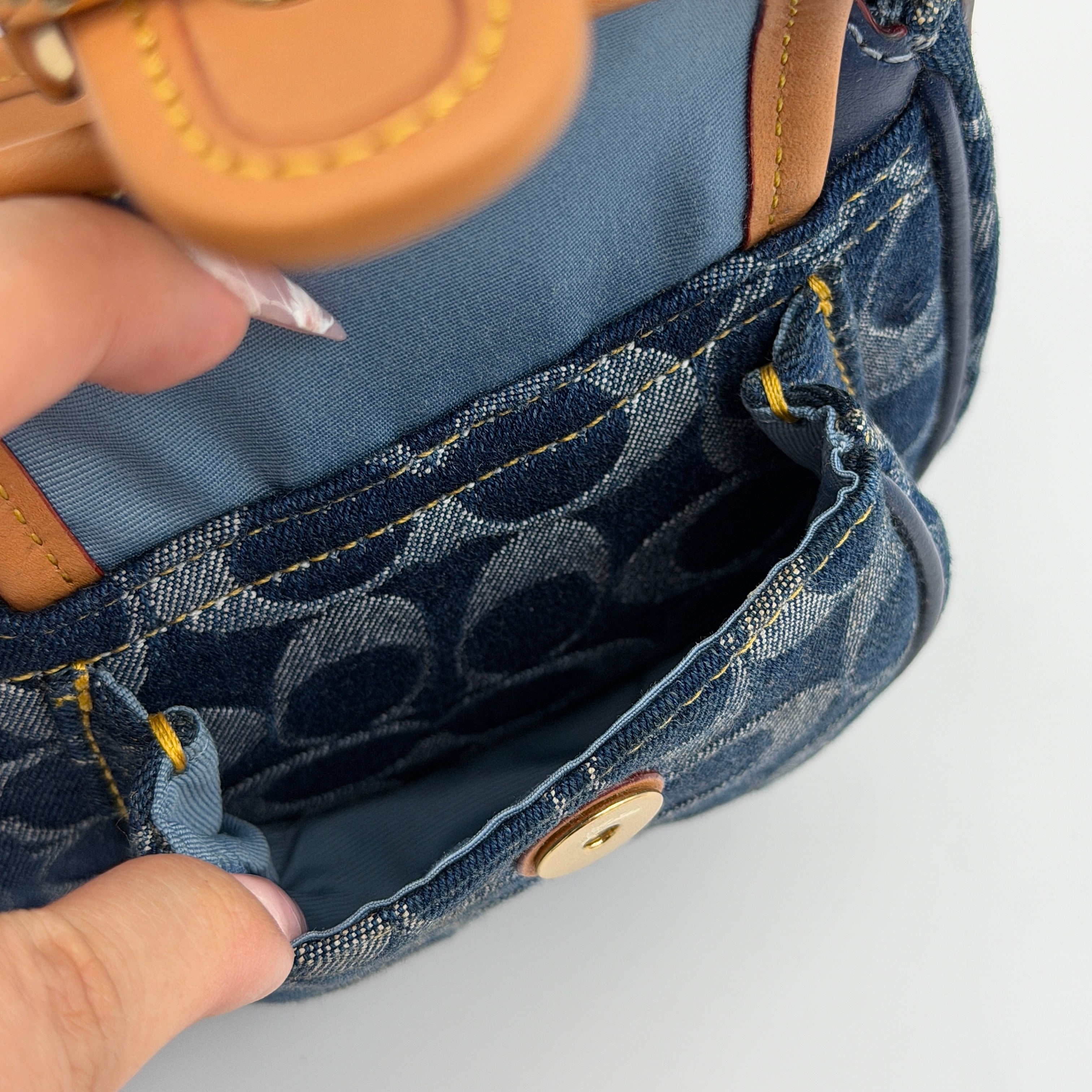 Coach Signature Ashton shoulder bag in blue denim and tan leather with gold hardware, shown with removable strap and dust bag.