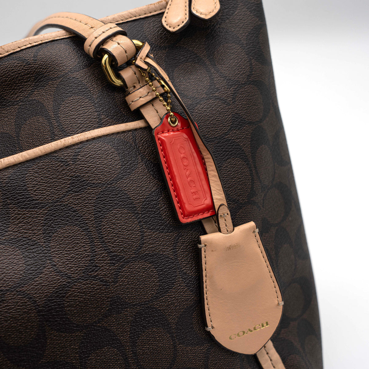 Coach Signature Peyton Pocket tote bag in brown canvas with tan leather trim, shown with both handles and detachable strap.