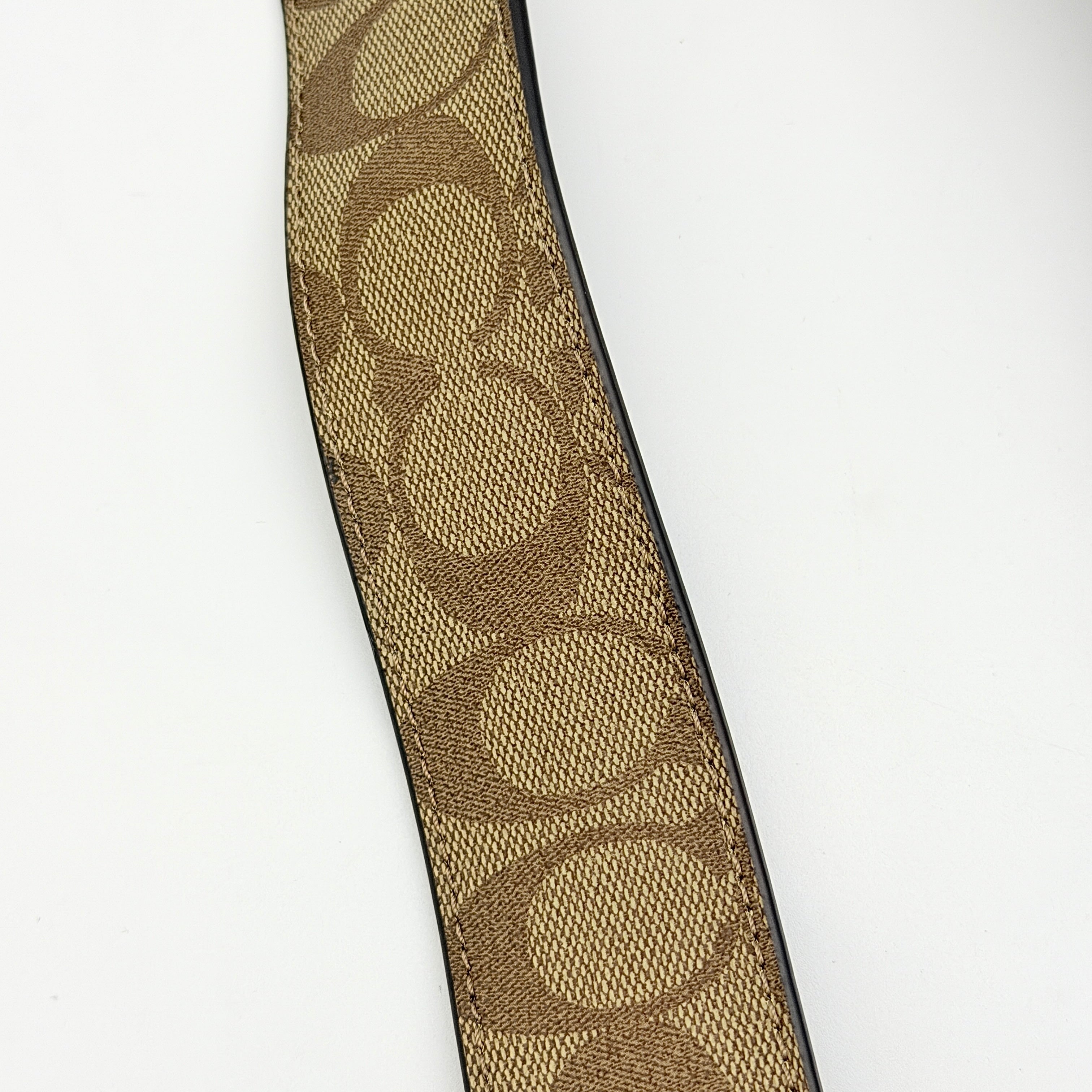 Coach Signature Canvas strap in brown with gold-tone hardware and monogram pattern, shown with Coach dust bag.