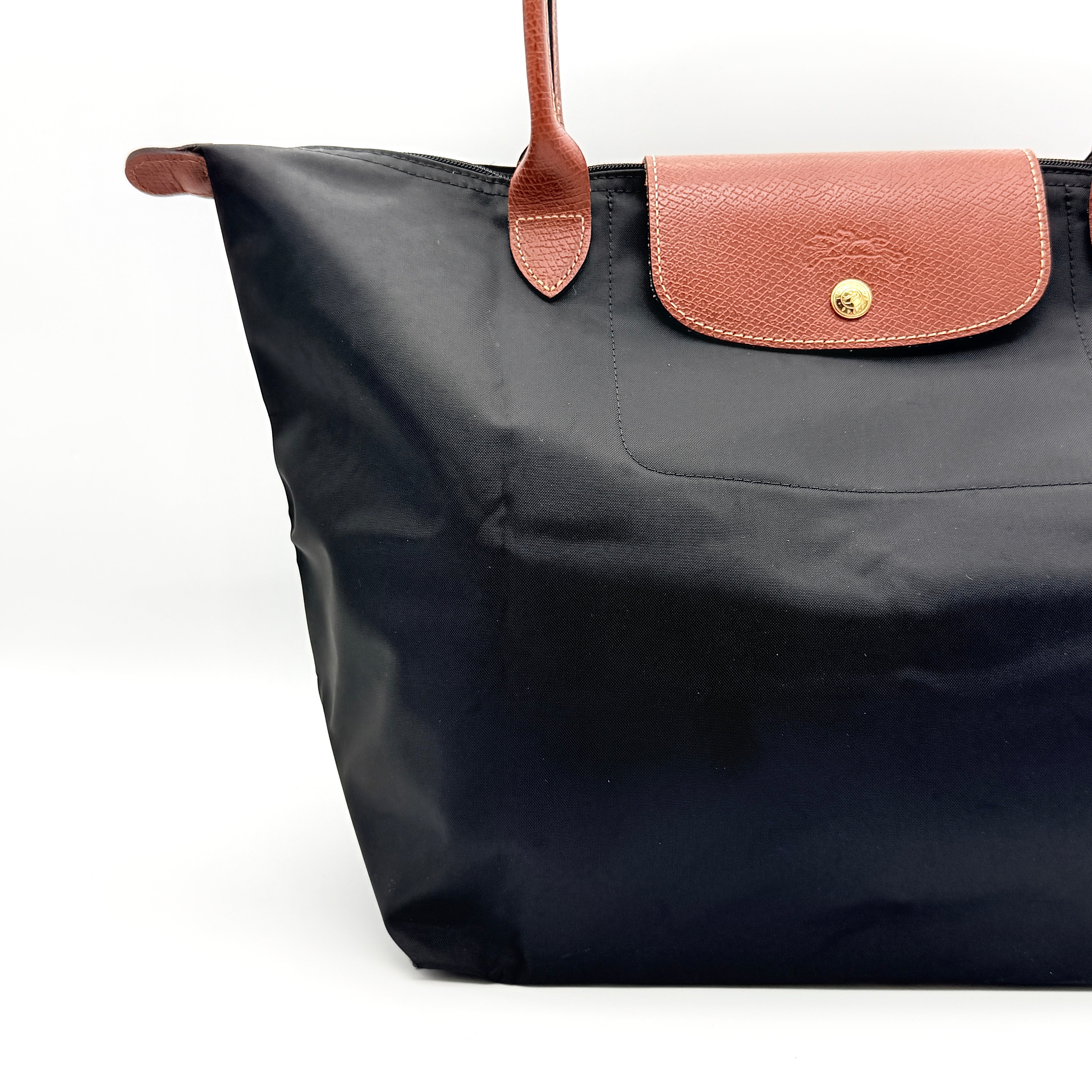 Longchamp Le Pliage Original Tote Bag in black with brown leather handles and flap, photographed against a white background.