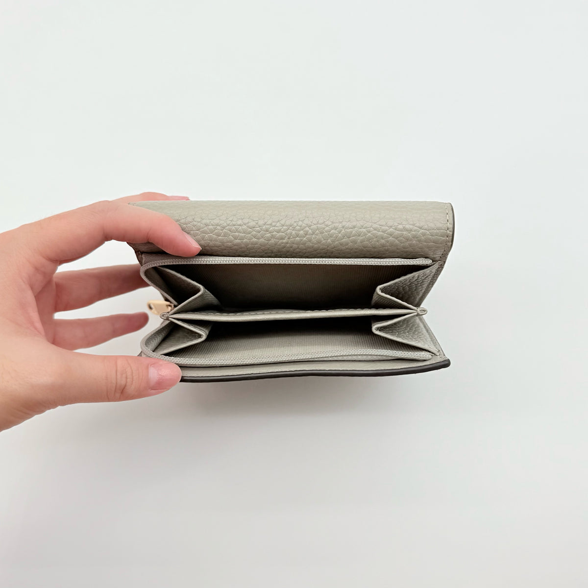 Furla Dafne Trifold Wallet in grey pebbled leather with gold-tone hardware and trifold interior, shown with original dust bag.