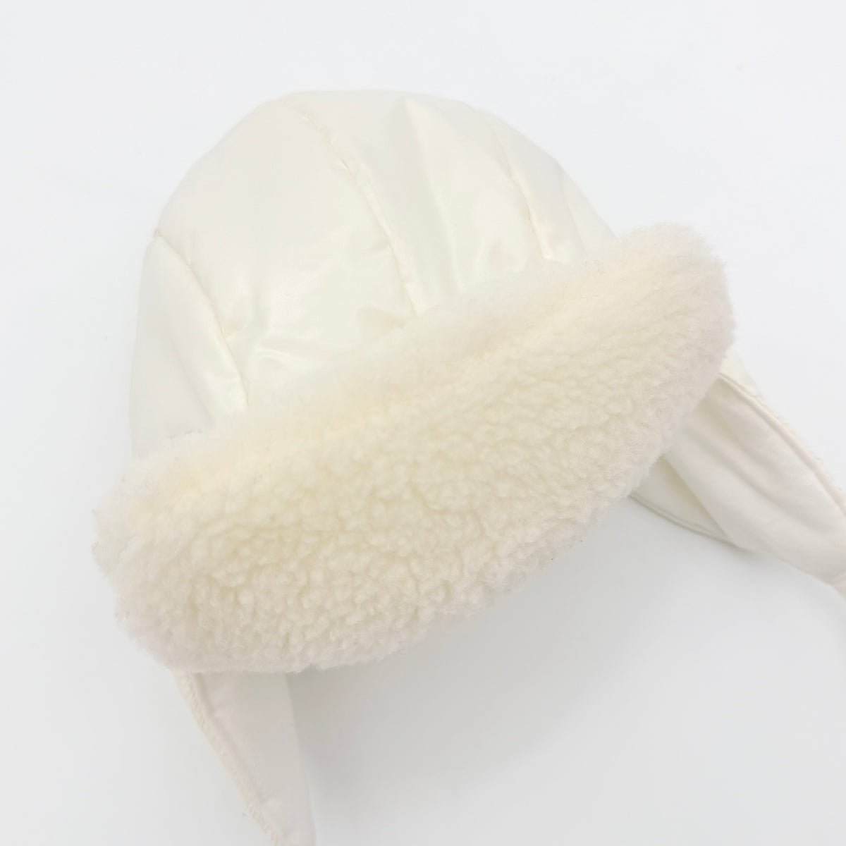 Moncler ivory quilted trapper hat with plush faux fur trim and signature logo patch displayed on white background.