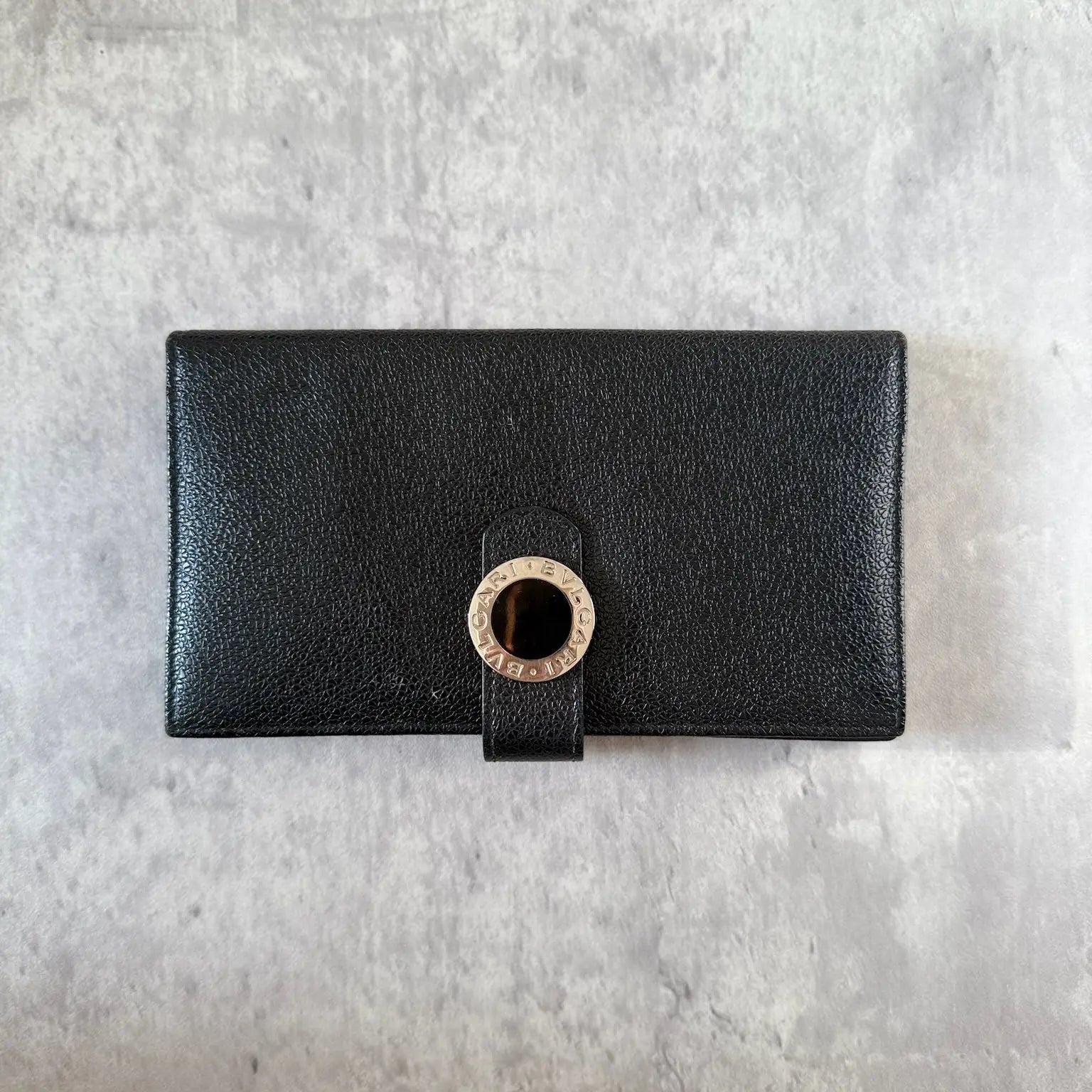 Bvlgari Black Leather Signature Ring Fold Long Wallet with a logo ring closure and red interior.