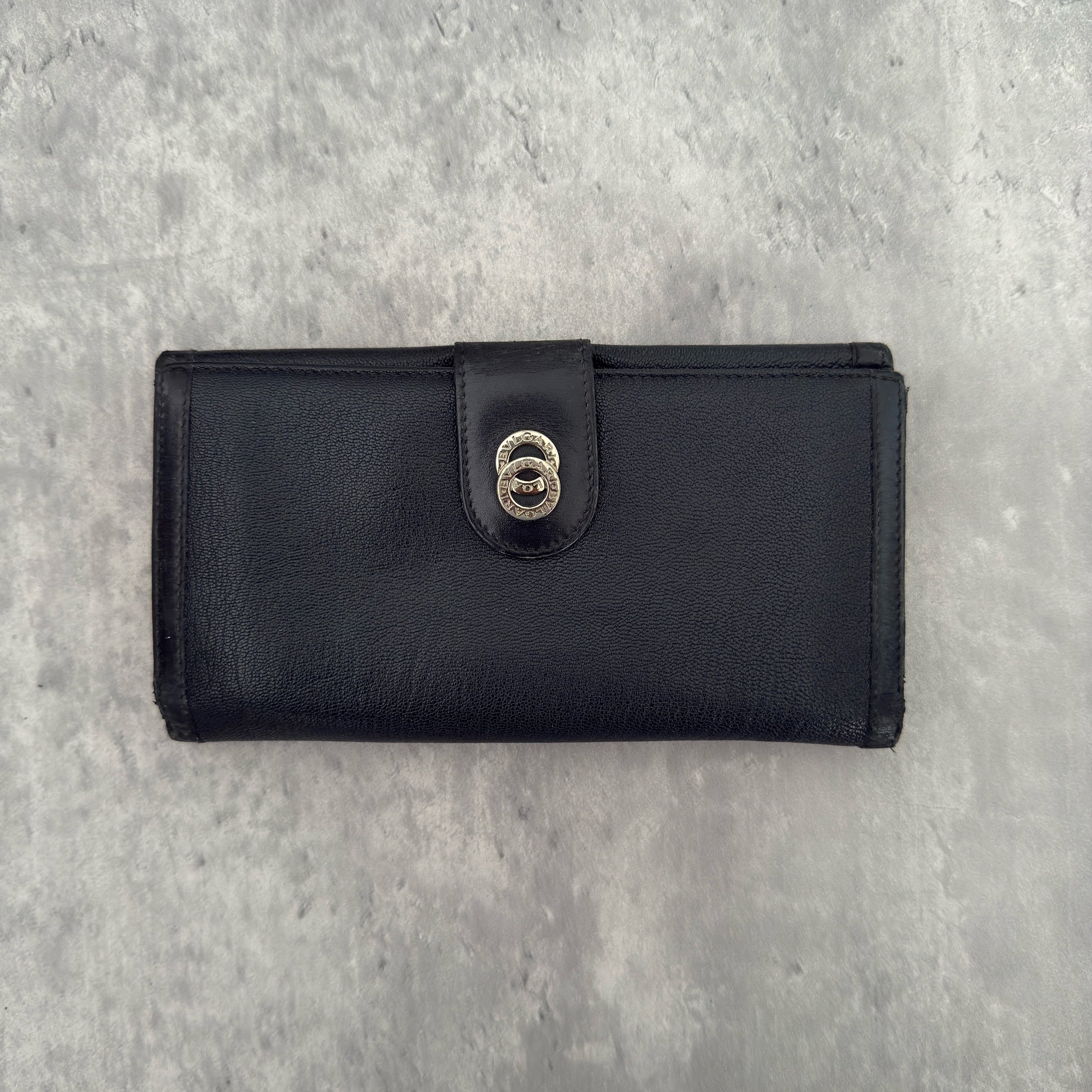 Bvlgari Doppio Tondo Bifold Long Wallet in black leather, featuring a silver-tone logo clasp, red fabric interior, and multiple compartments.