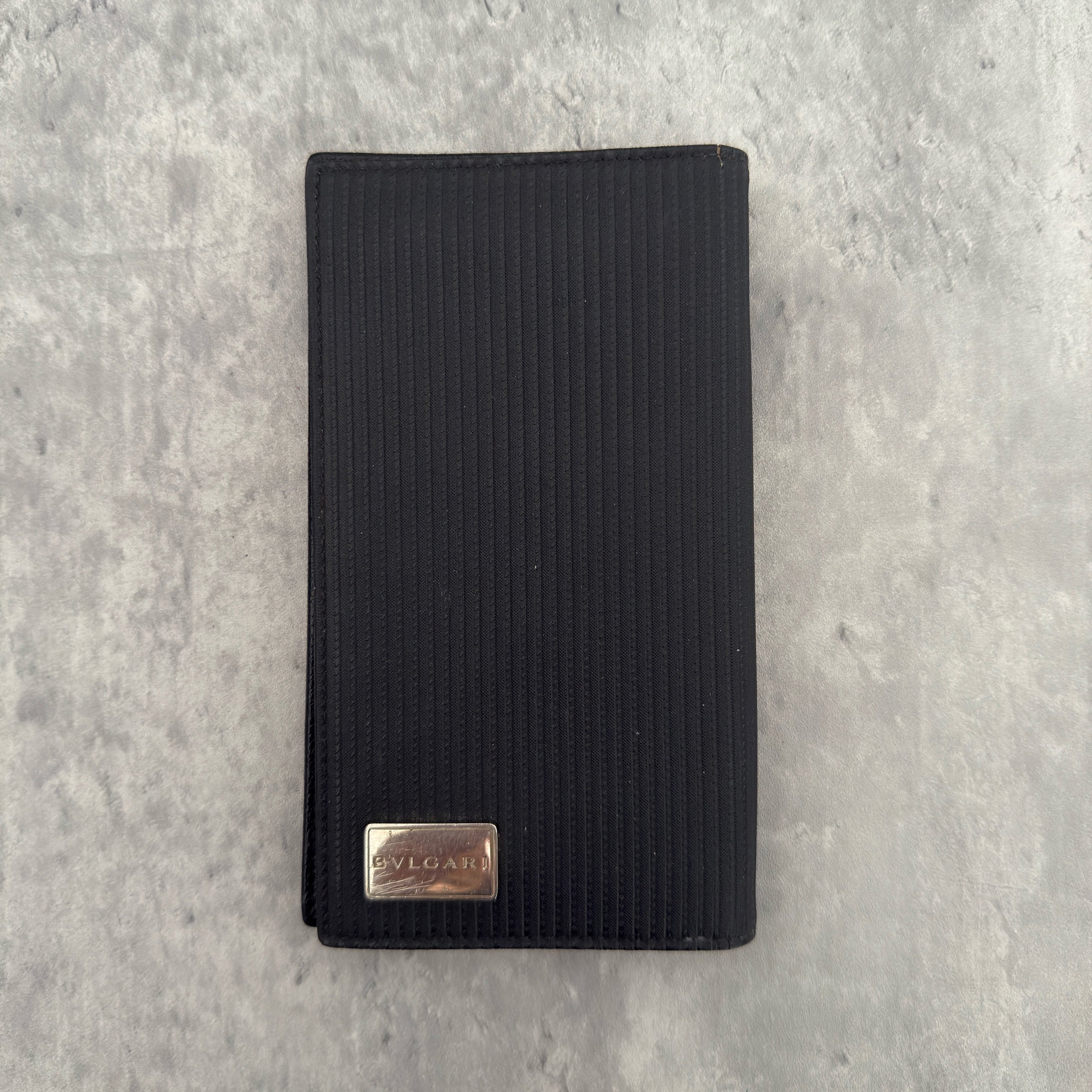 Bvlgari Ribbed Nylon Long Bifold Wallet in black with a silver-tone metal plaque logo, featuring multiple compartments and a sleek ribbed texture.