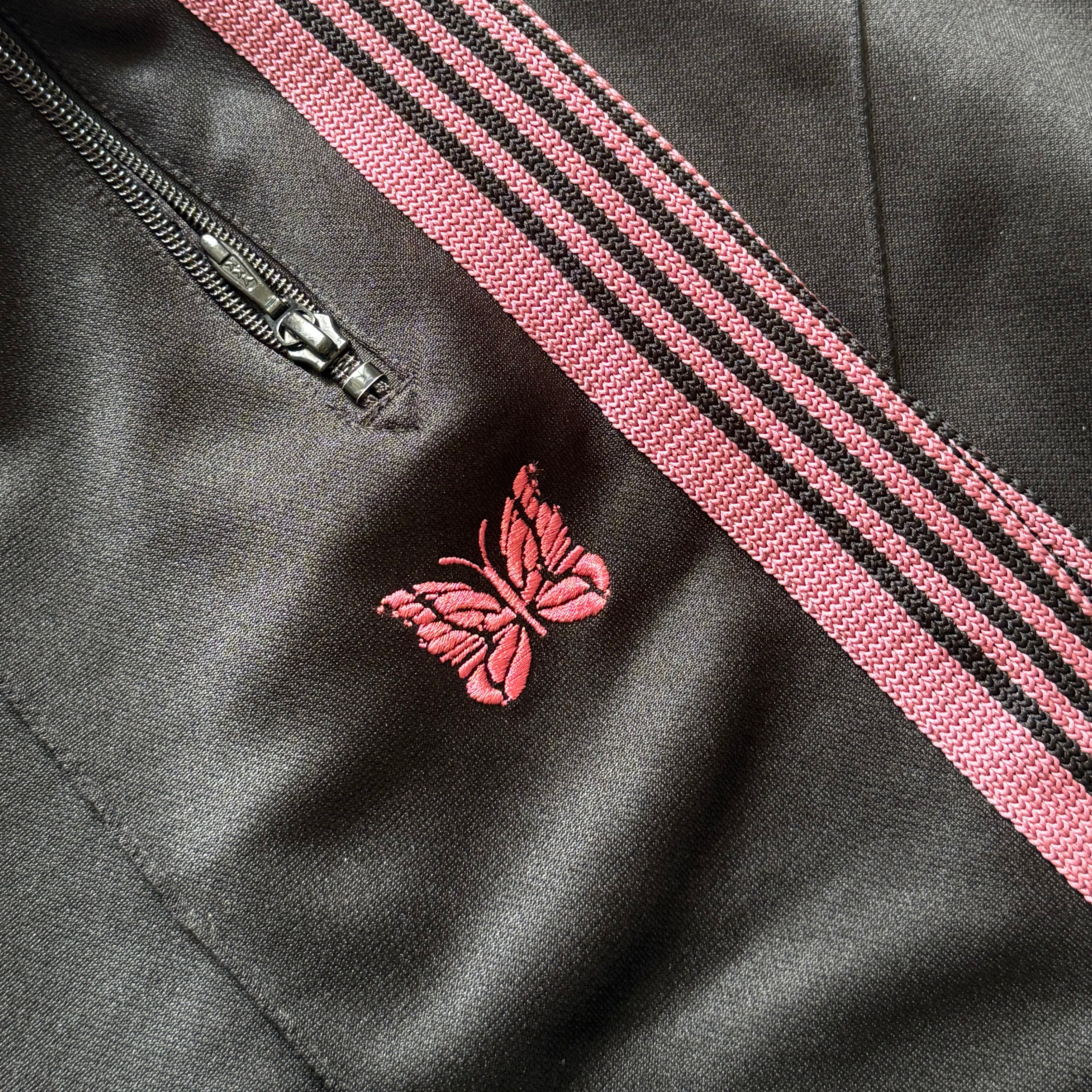 Needles Track Pants Black and Pink, featuring pink taping and butterfly embroidery with zippered pockets.