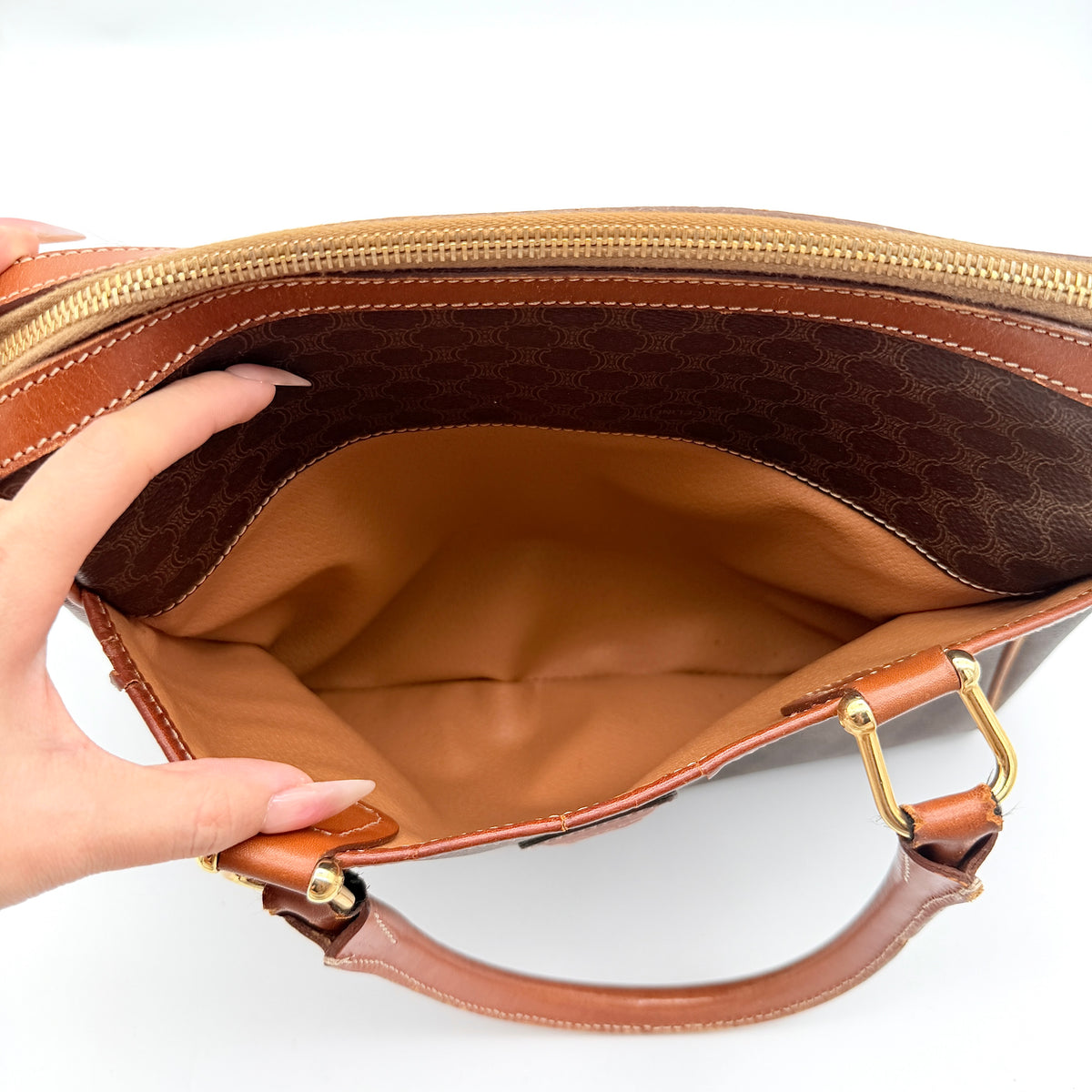 Celine Triomphe Macadam Boston Bag in brown coated canvas with tan leather handles and gold hardware on a white background.