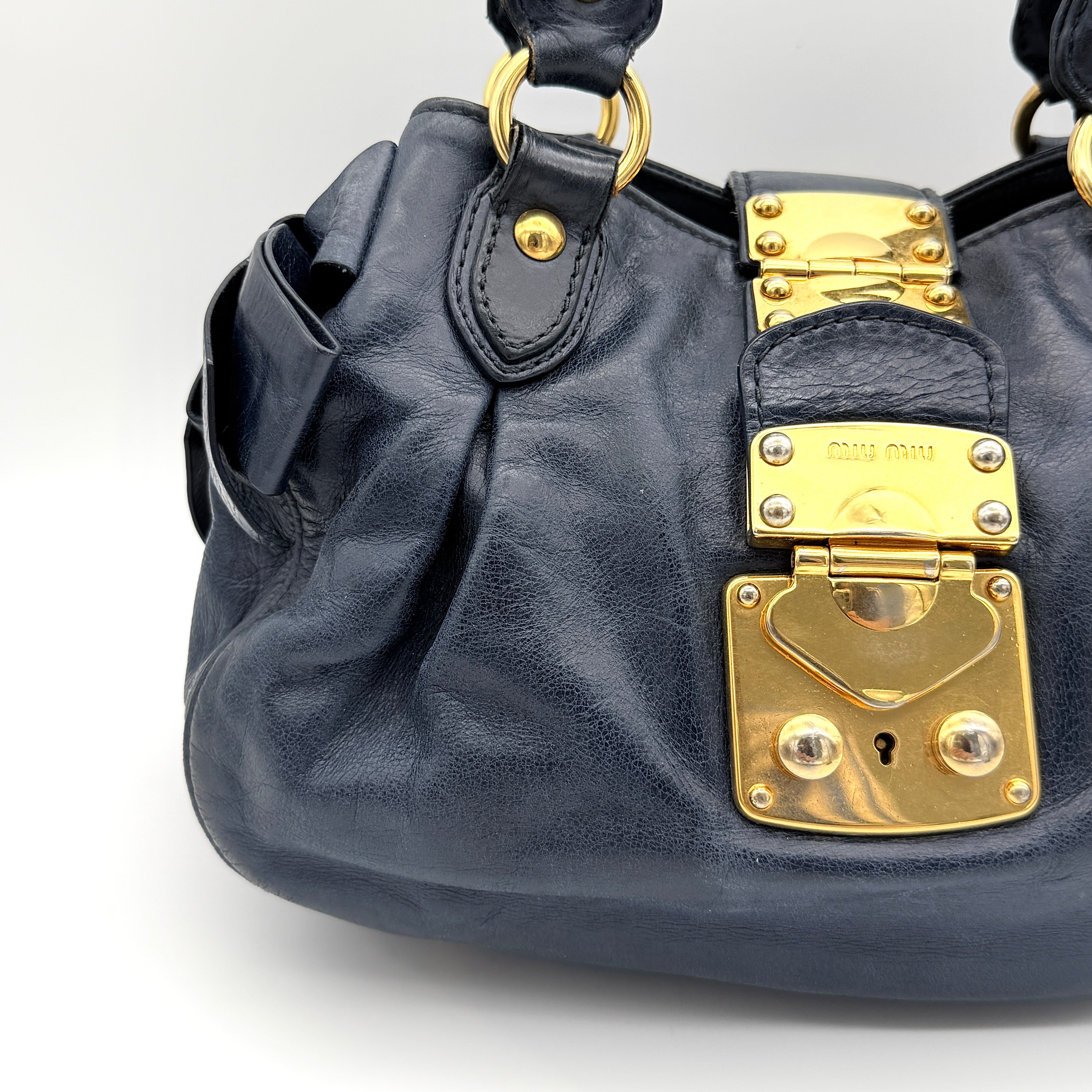 Miu Miu navy blue Vitello Lux Bow Satchel with gold-tone hardware, detachable strap, and dust bag.