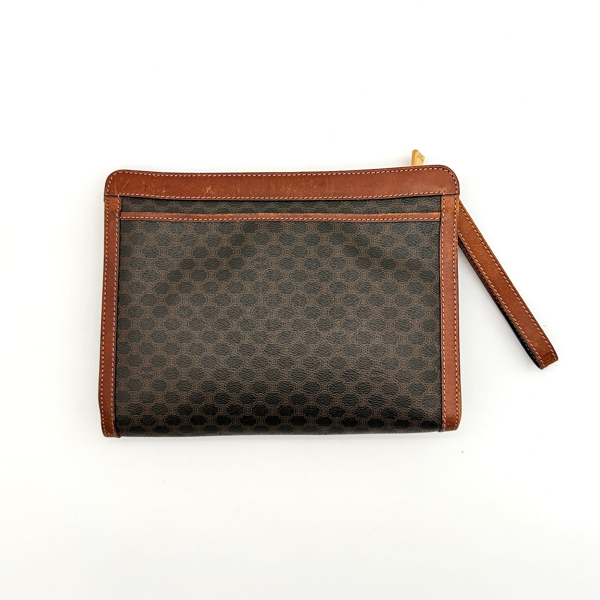Celine Triomphe Macadam clutch bag in brown canvas with tan leather trim and gold hardware, shown with wrist strap.