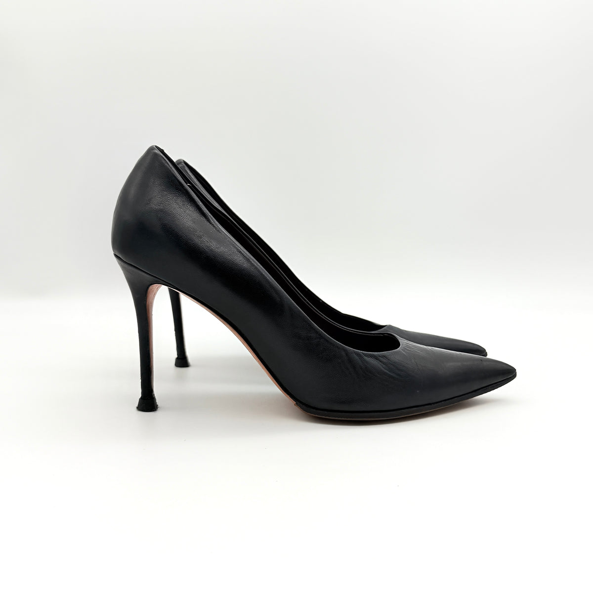 A pair of black leather Celine stiletto heels with pointed toes and burgundy insoles, shown in a softly lit studio setting.
