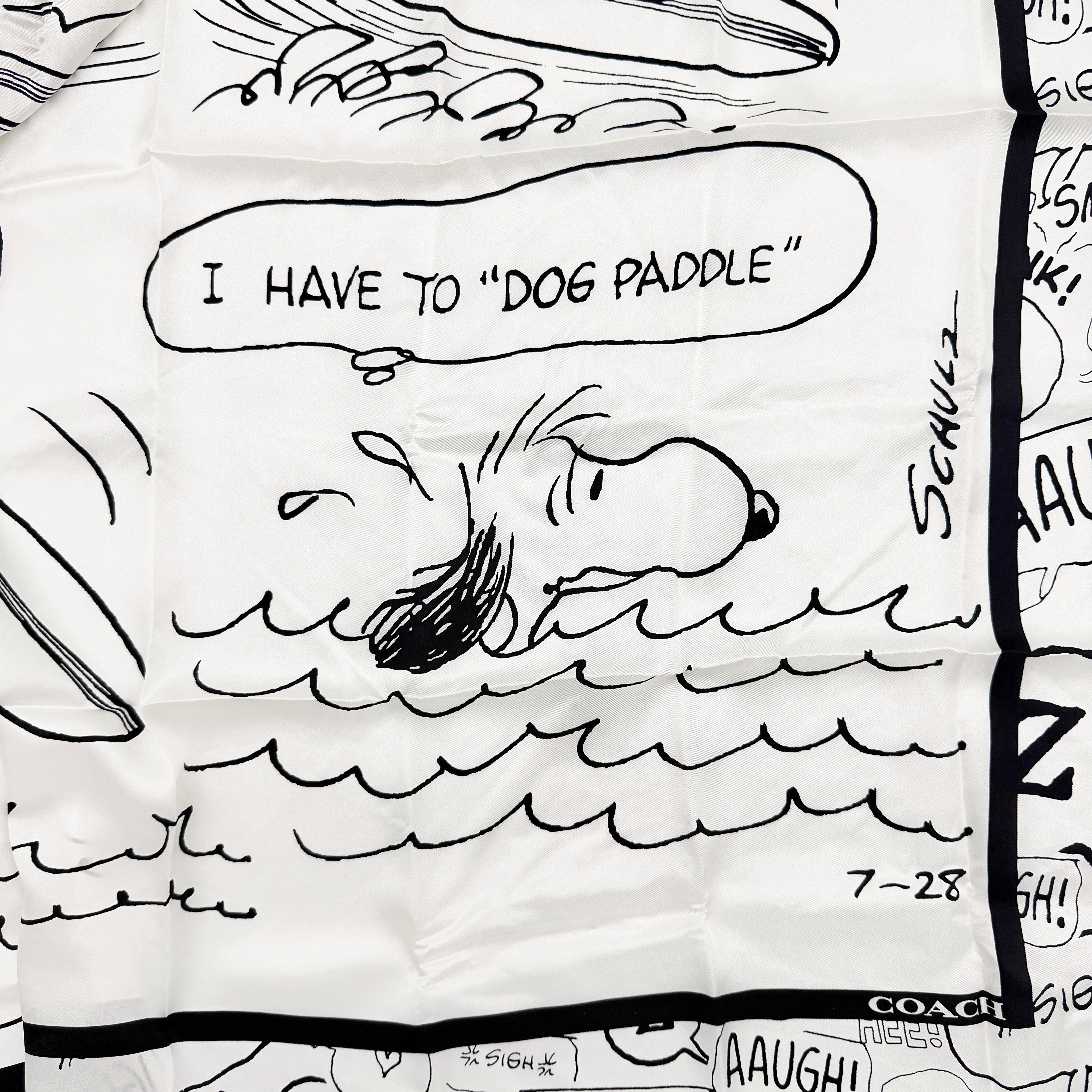 Coach x Peanuts black and white silk scarf featuring a Snoopy surfing comic print, shown with Coach packaging and tags.