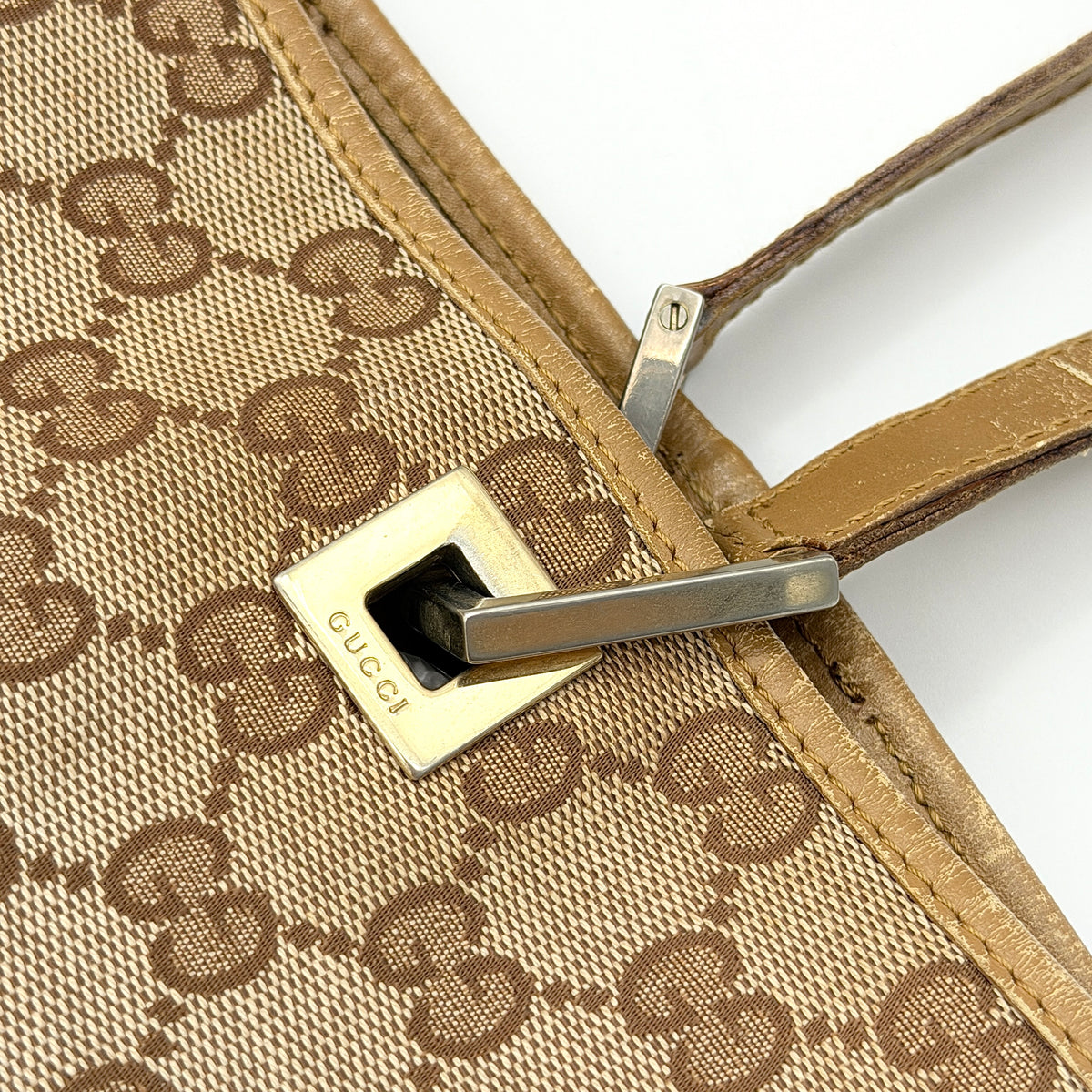 Front-facing Gucci GG Monogram Tote Bag in beige canvas with brown leather trim and double handles.
