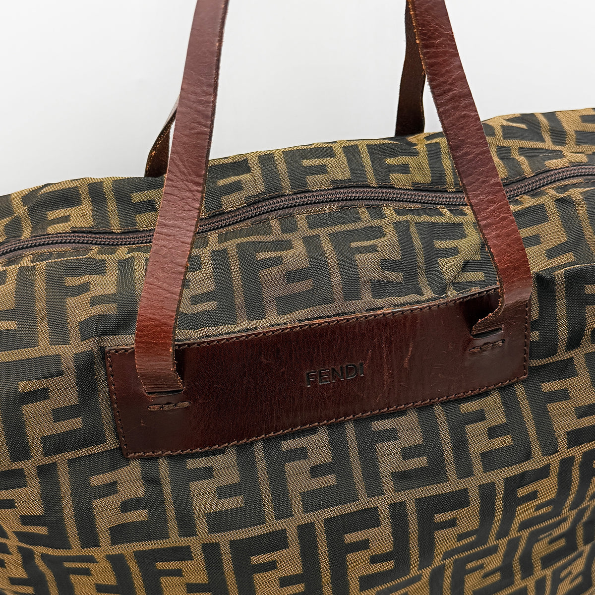 Fendi FF Zucca foldable tote bag in brown canvas with leather top handles and all-over monogram, shown standing upright.