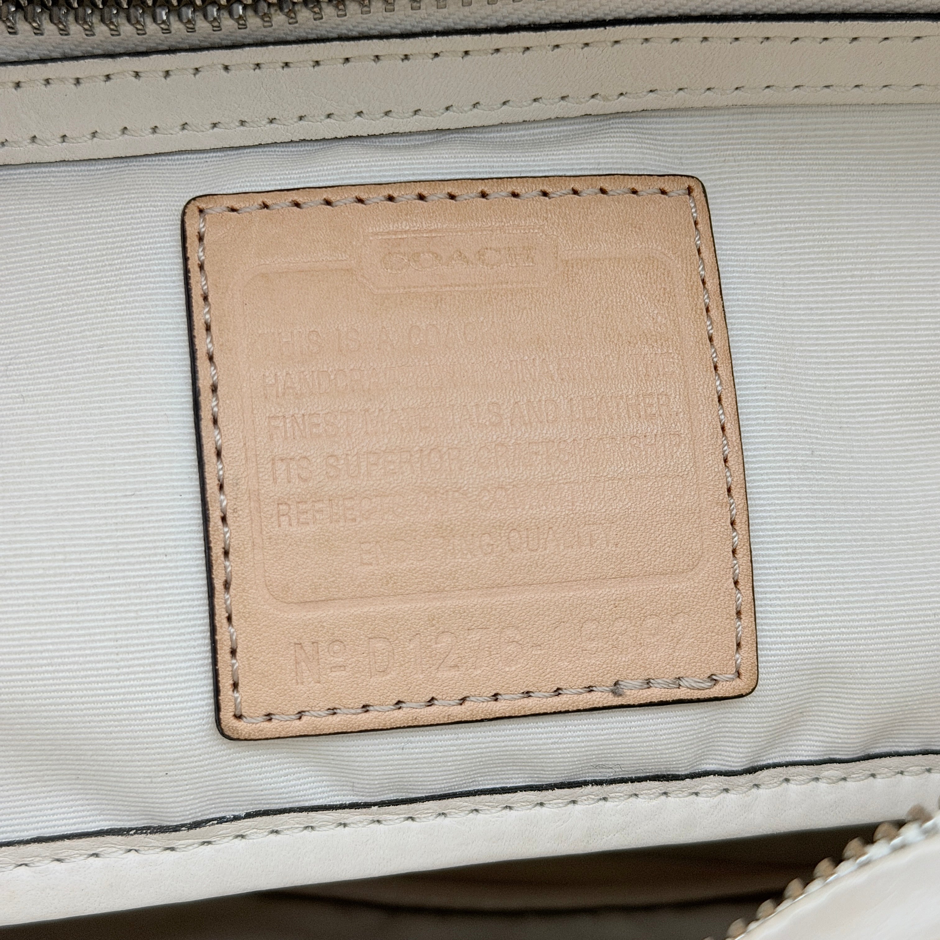 Coach Hampton Weekend perforated cream and grey leather tote bag with tan handles and a silver Coach charm, displayed against a white background.