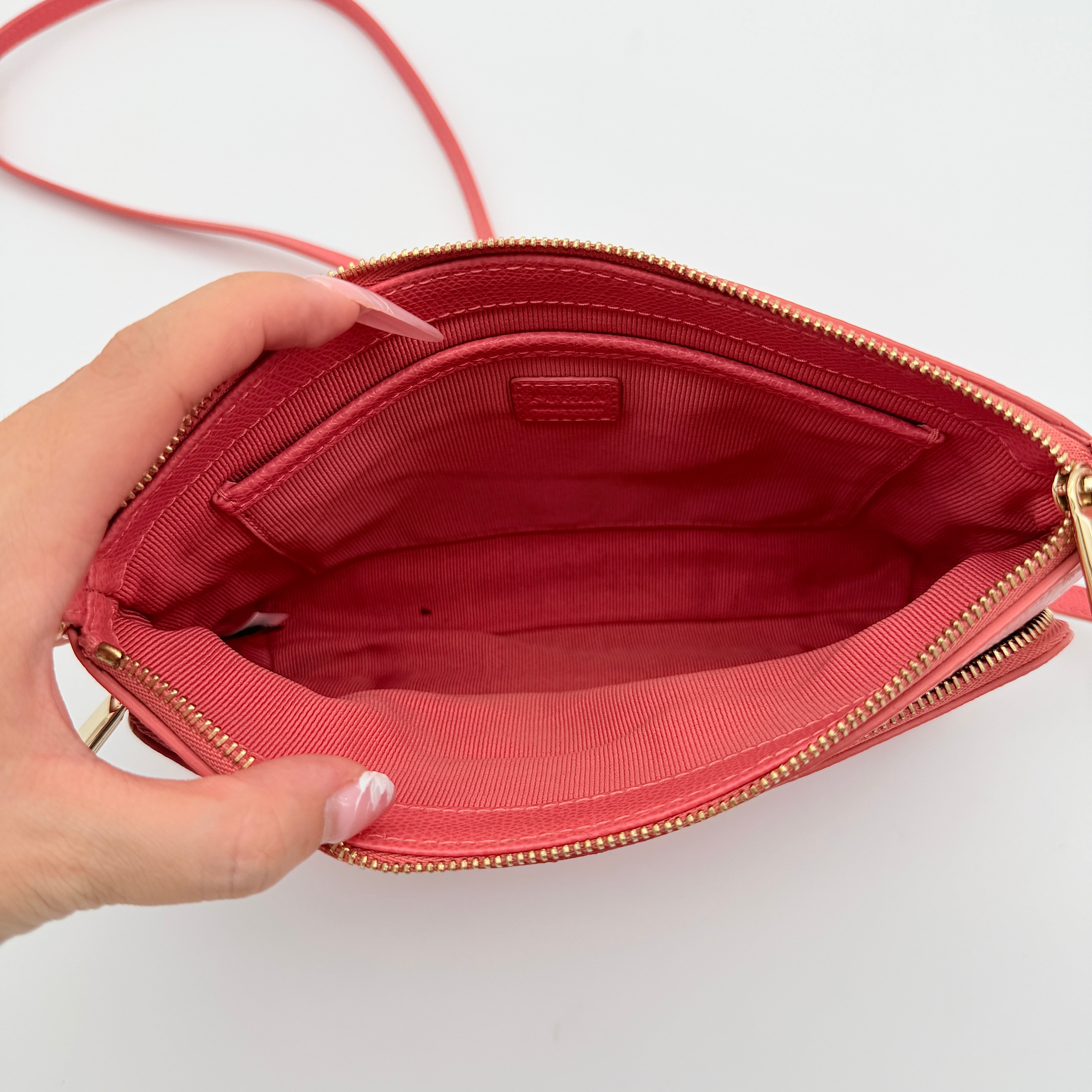 Furla pink leather crossbody bag with gold zip and adjustable strap, photographed flat on a white background.