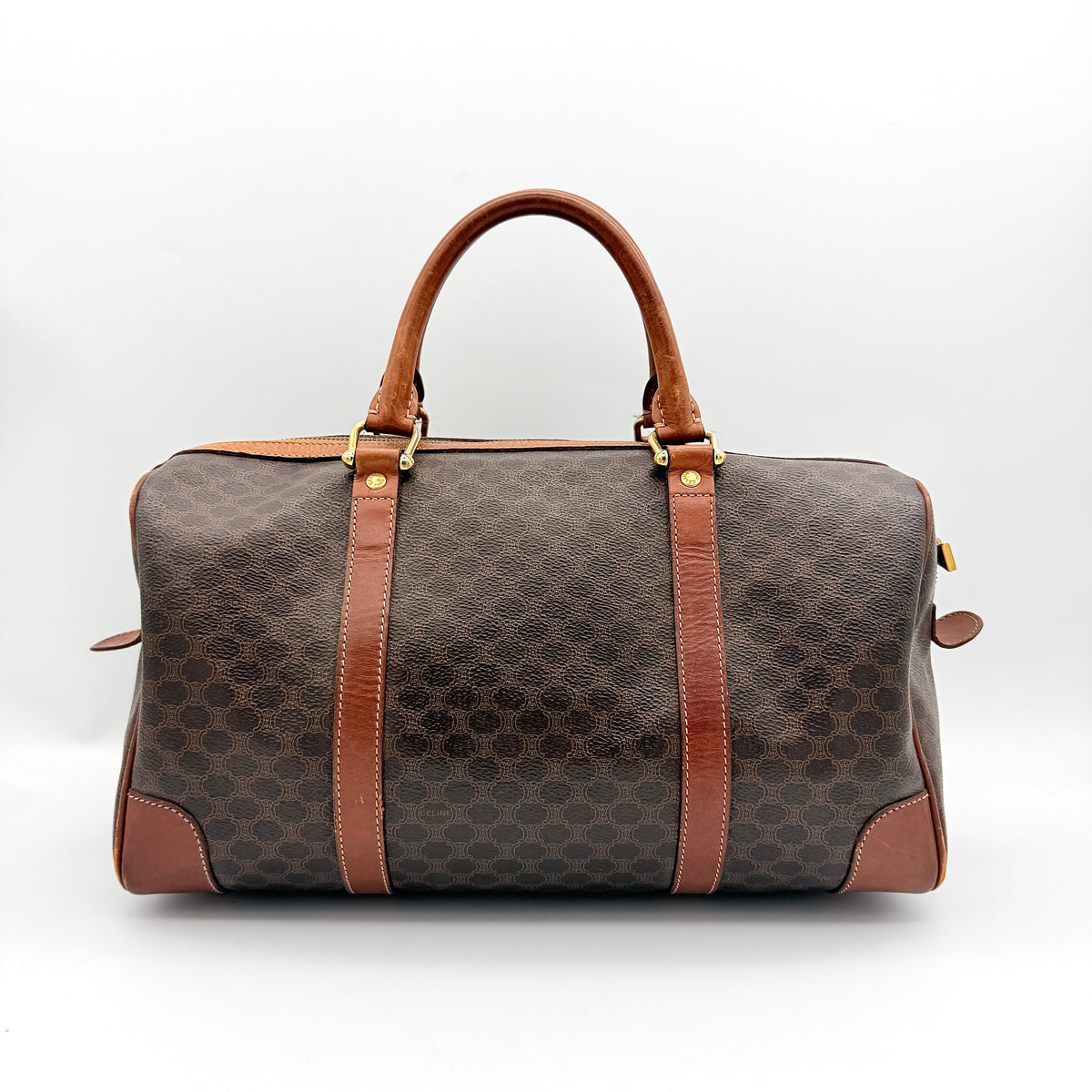 Celine Macadam Triomphe Boston Bag in brown coated canvas with tan leather and gold-tone hardware, shown against a white background.