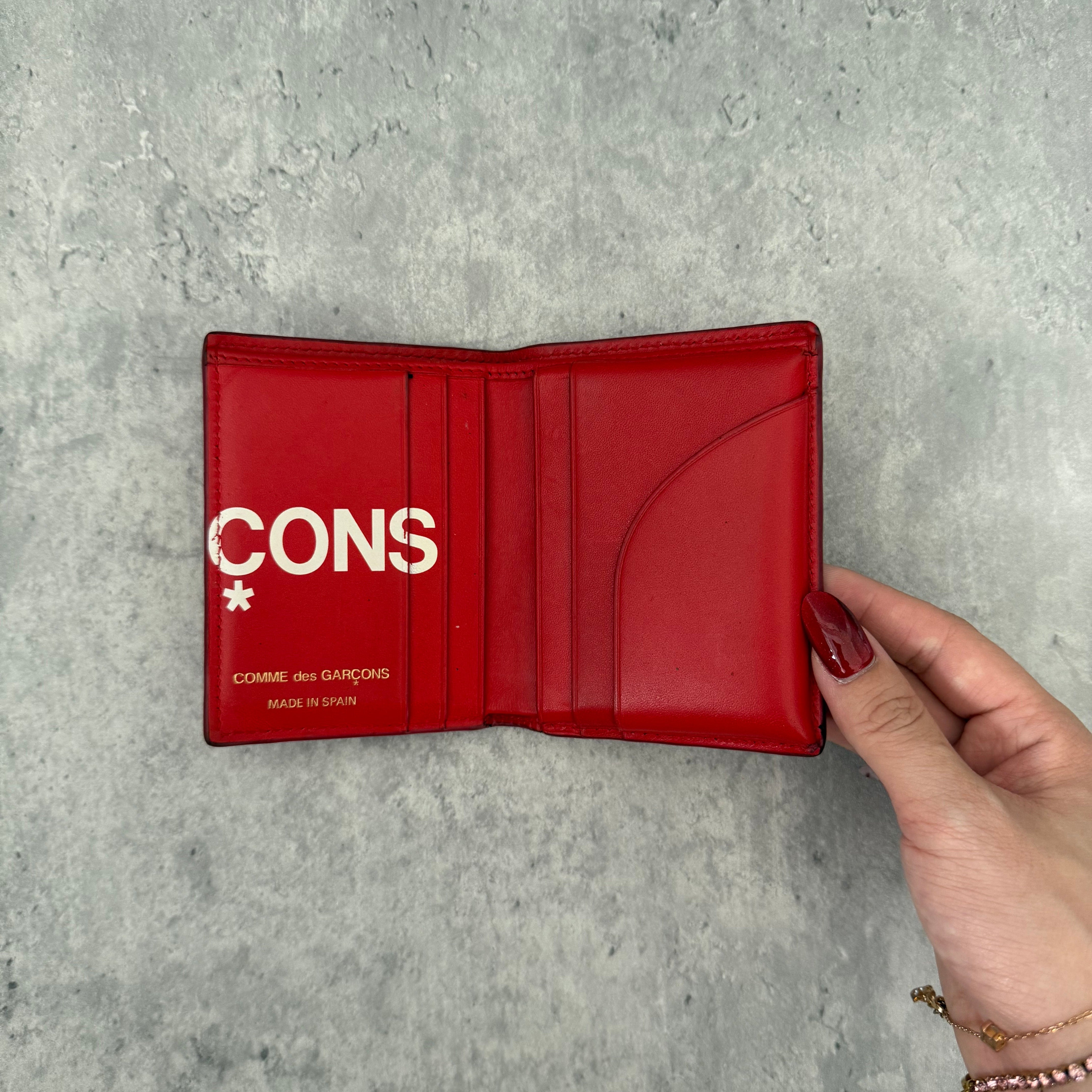 COMME des GARÇONS Huge Logo Red Leather Wallet with oversized white print and multiple card slots in a bi-fold design.