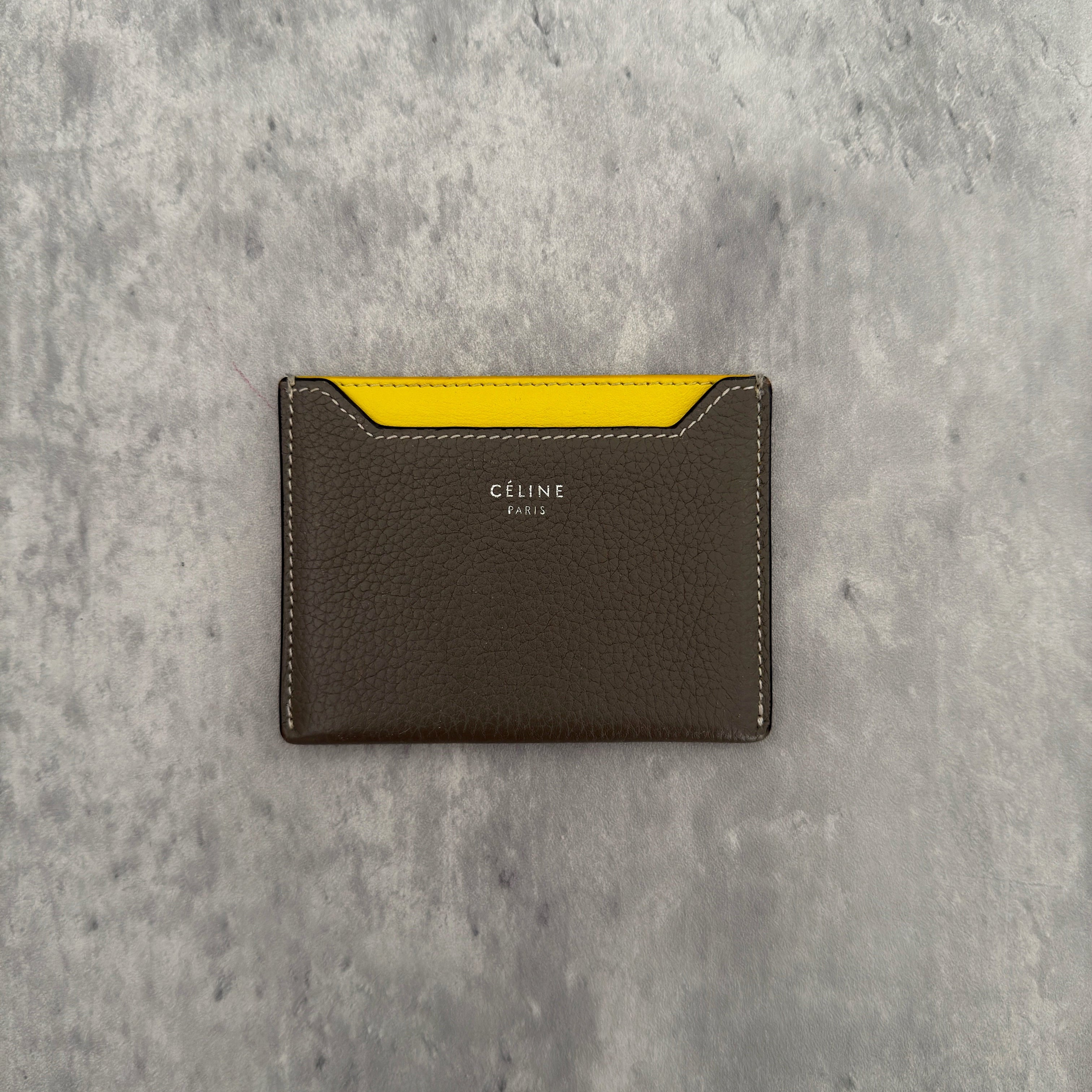 Celine Drummed Calfskin Bi-Color Cardholder in olive green and yellow, featuring a minimalist design with multiple card slots and central pocket.