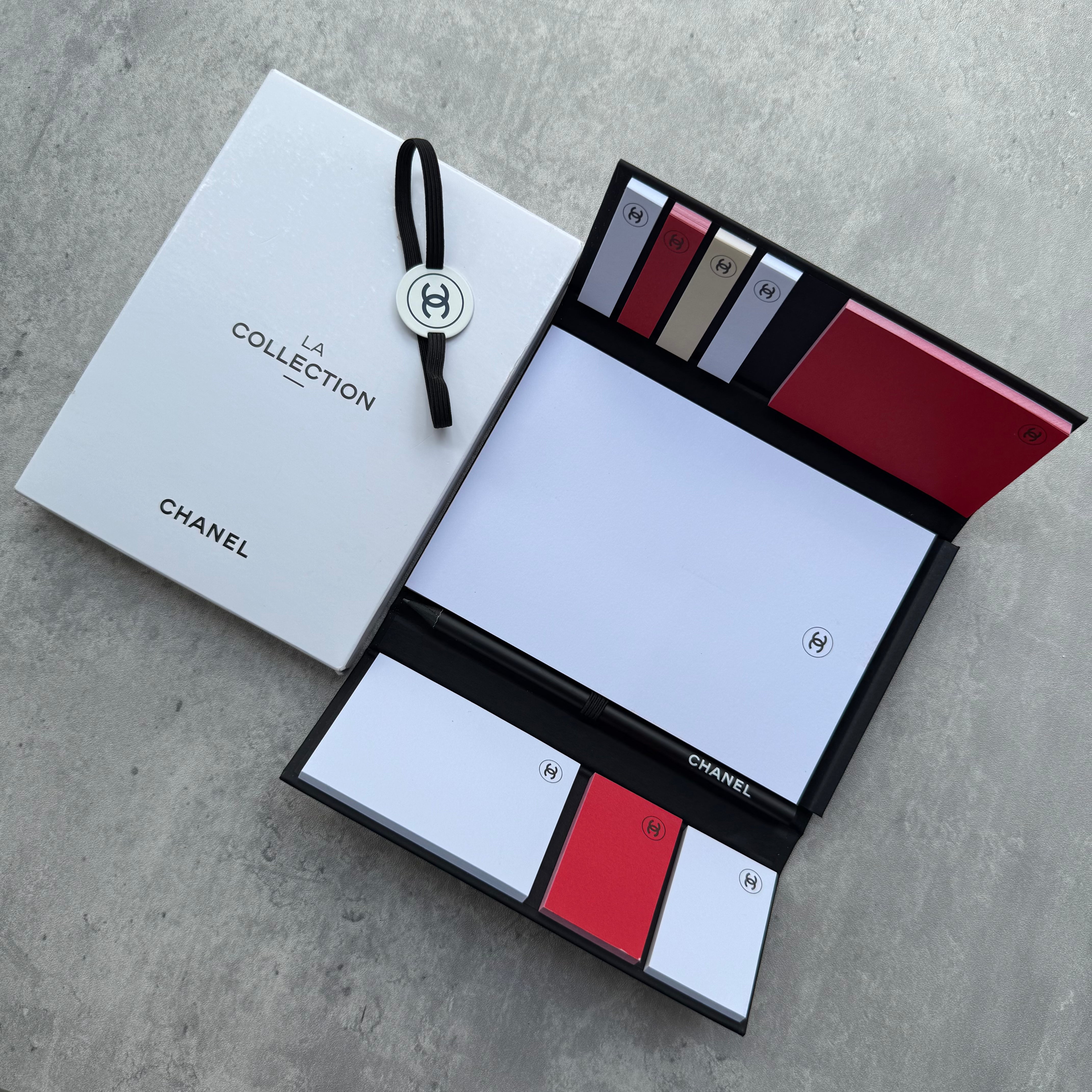 Chanel La Collection Stationery Set with black case, silver CC medallion, and assorted notepads and sticky tabs.