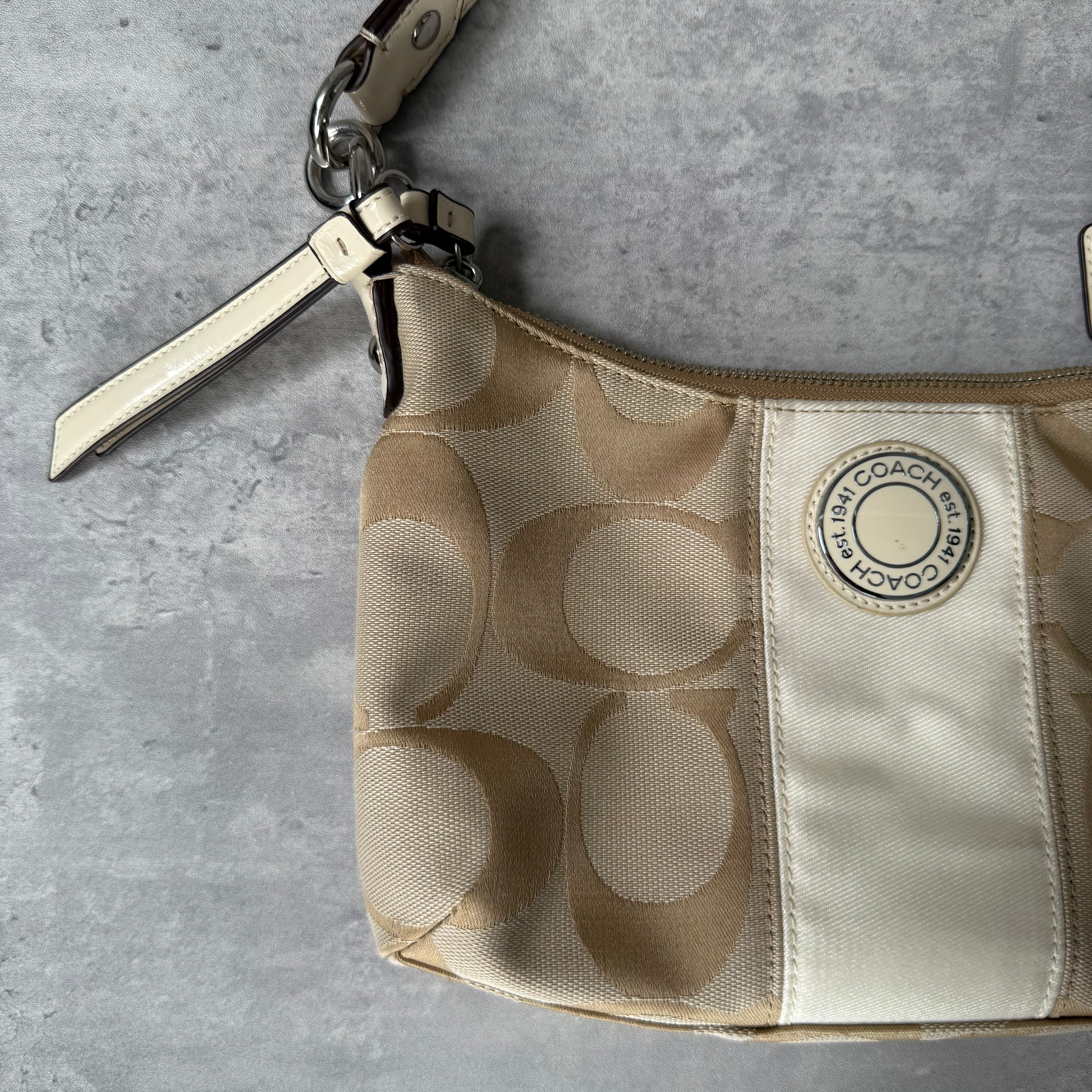 Coach 2-Way Signature Stripe Shoulder Bag in Beige and White with detachable strap, zip closure, and central white leather stripe with metal Coach emblem