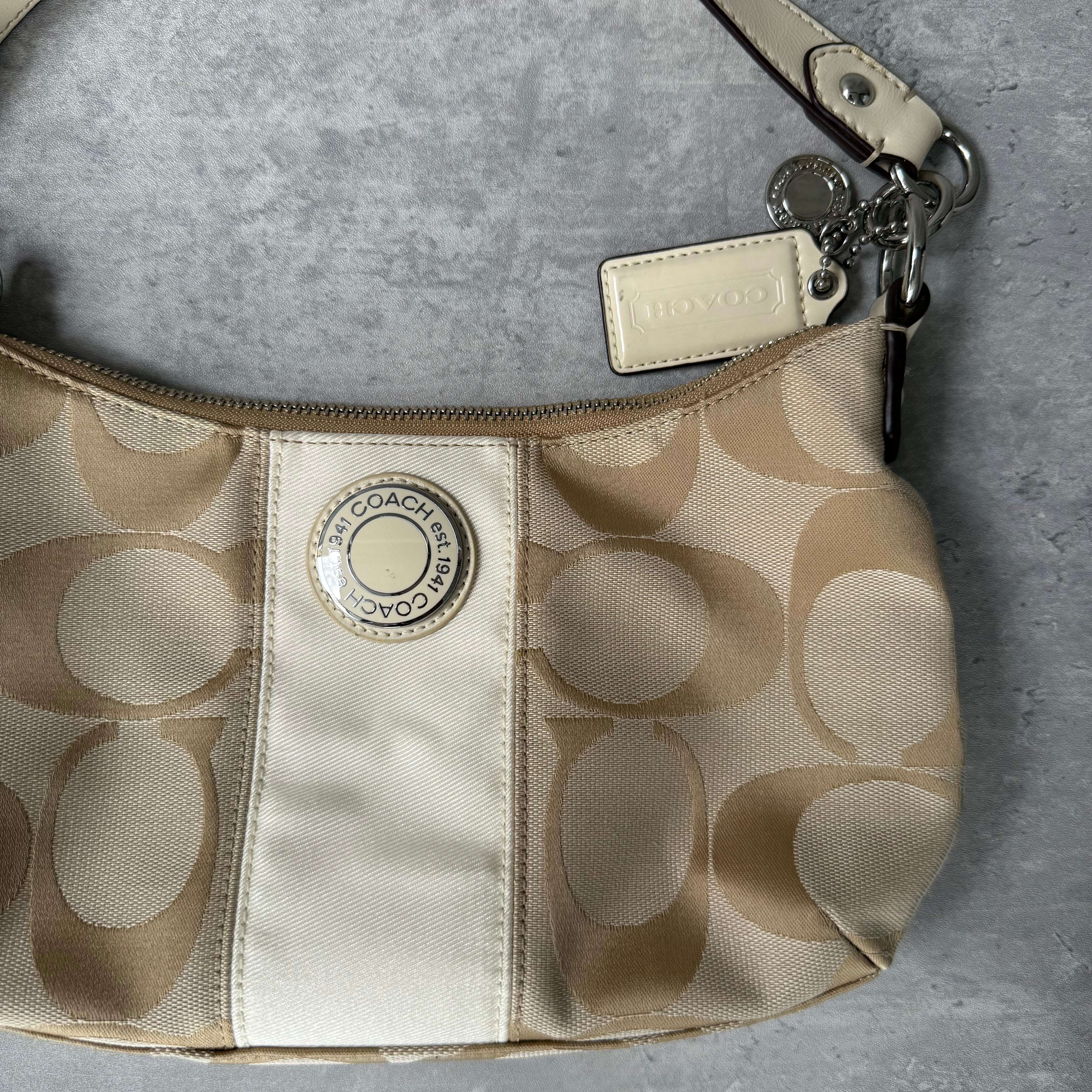 Coach 2-Way Signature Stripe Shoulder Bag in Beige and White with detachable strap, zip closure, and central white leather stripe with metal Coach emblem
