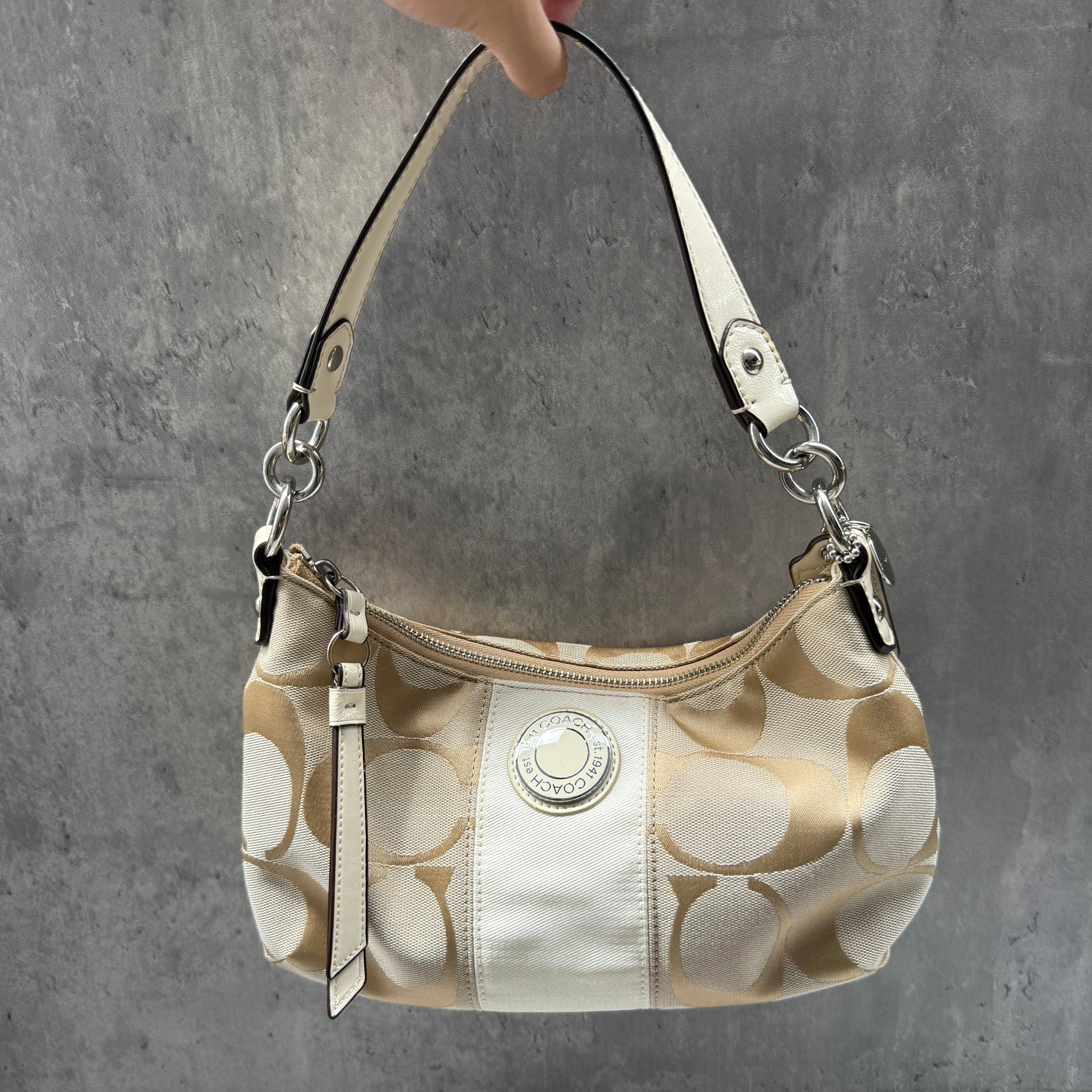 Coach 2-Way Signature Stripe Shoulder Bag in Beige and White with detachable strap, zip closure, and central white leather stripe with metal Coach emblem