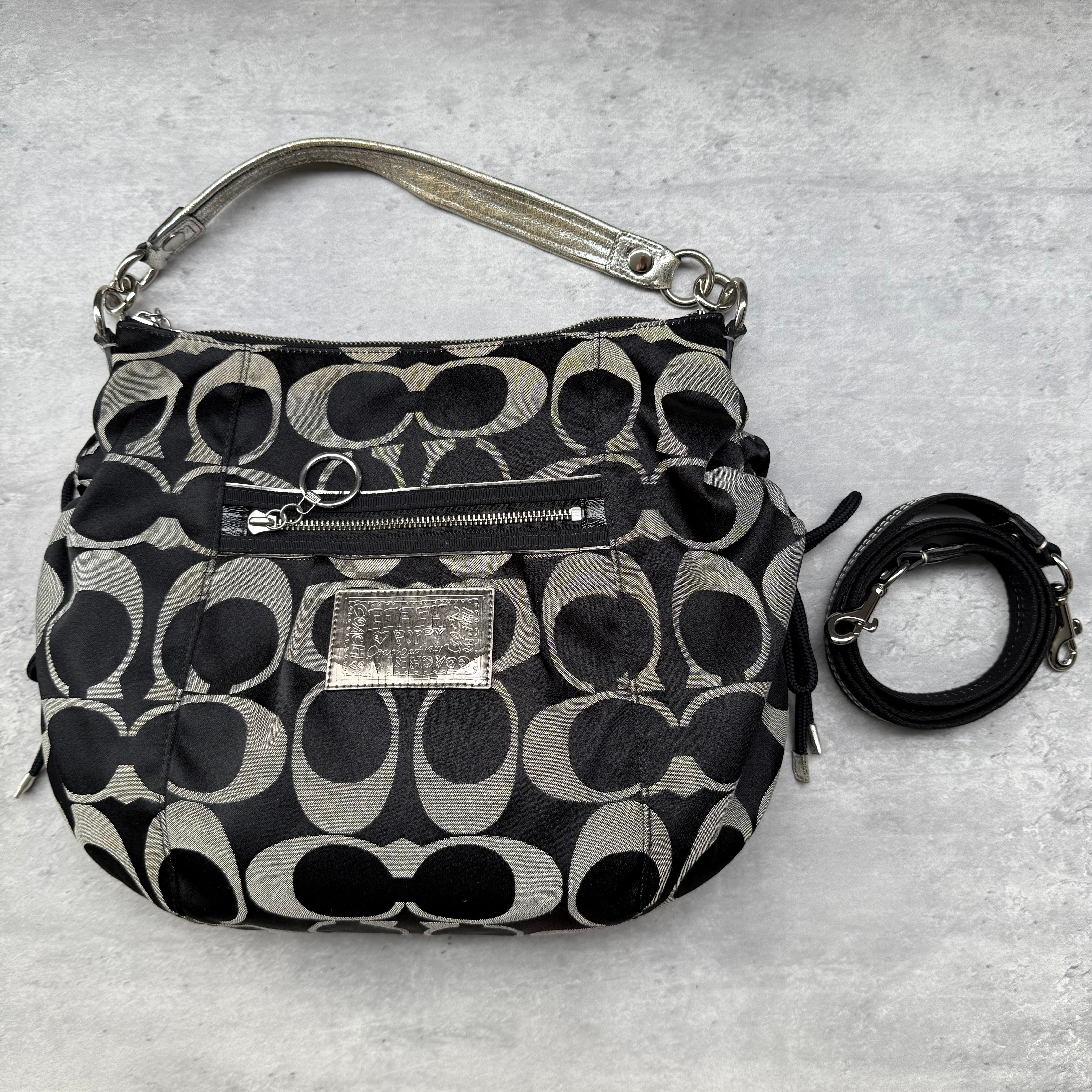 Coach 2Way Signature Poppy Shoulder Bag in black jacquard with silver trim, front zip pocket, detachable strap, and purple satin interior.