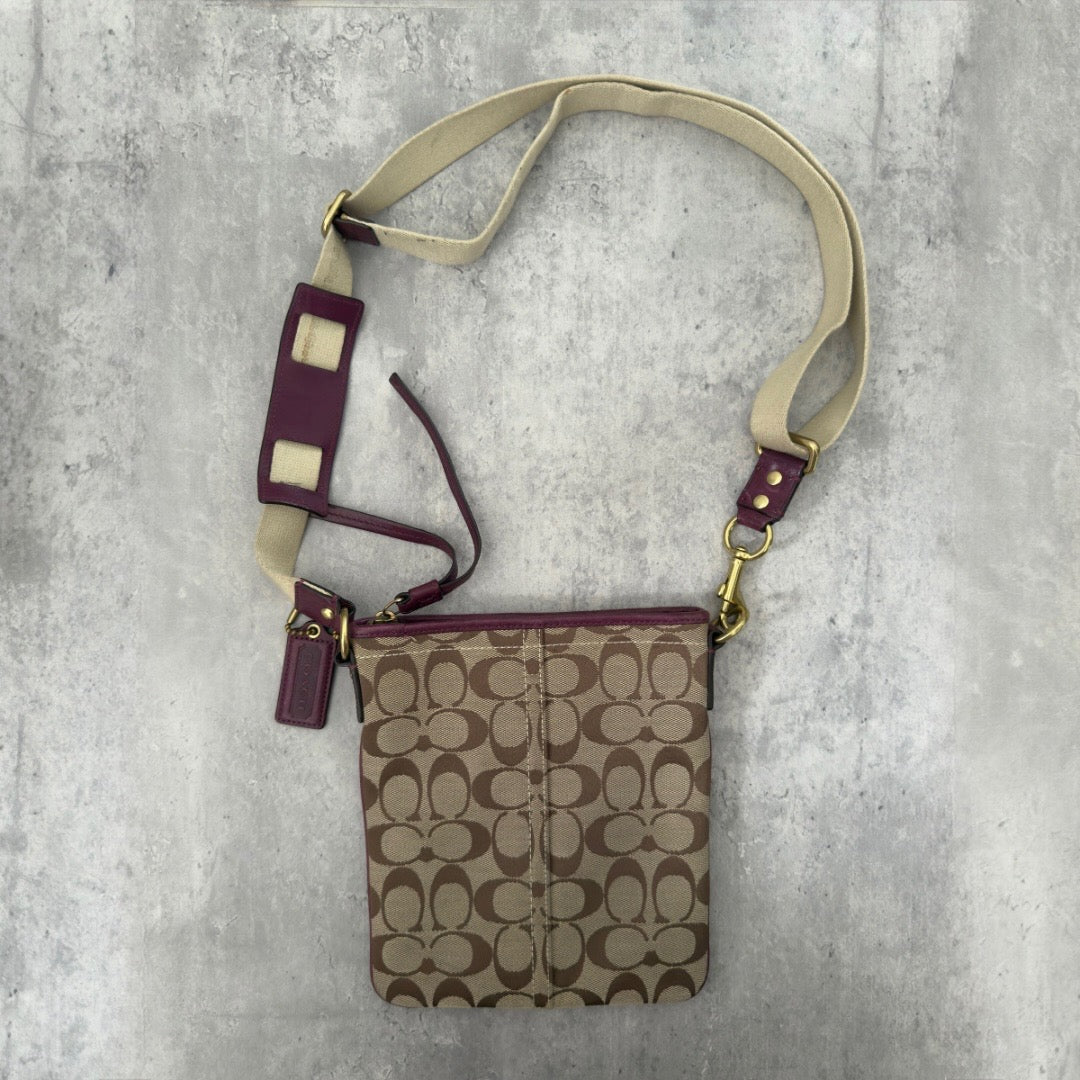 Coach Khaki Signature Crossbody Swing-pack in beige monogram canvas with purple leather trim, featuring an adjustable fabric strap and zippered top closure.