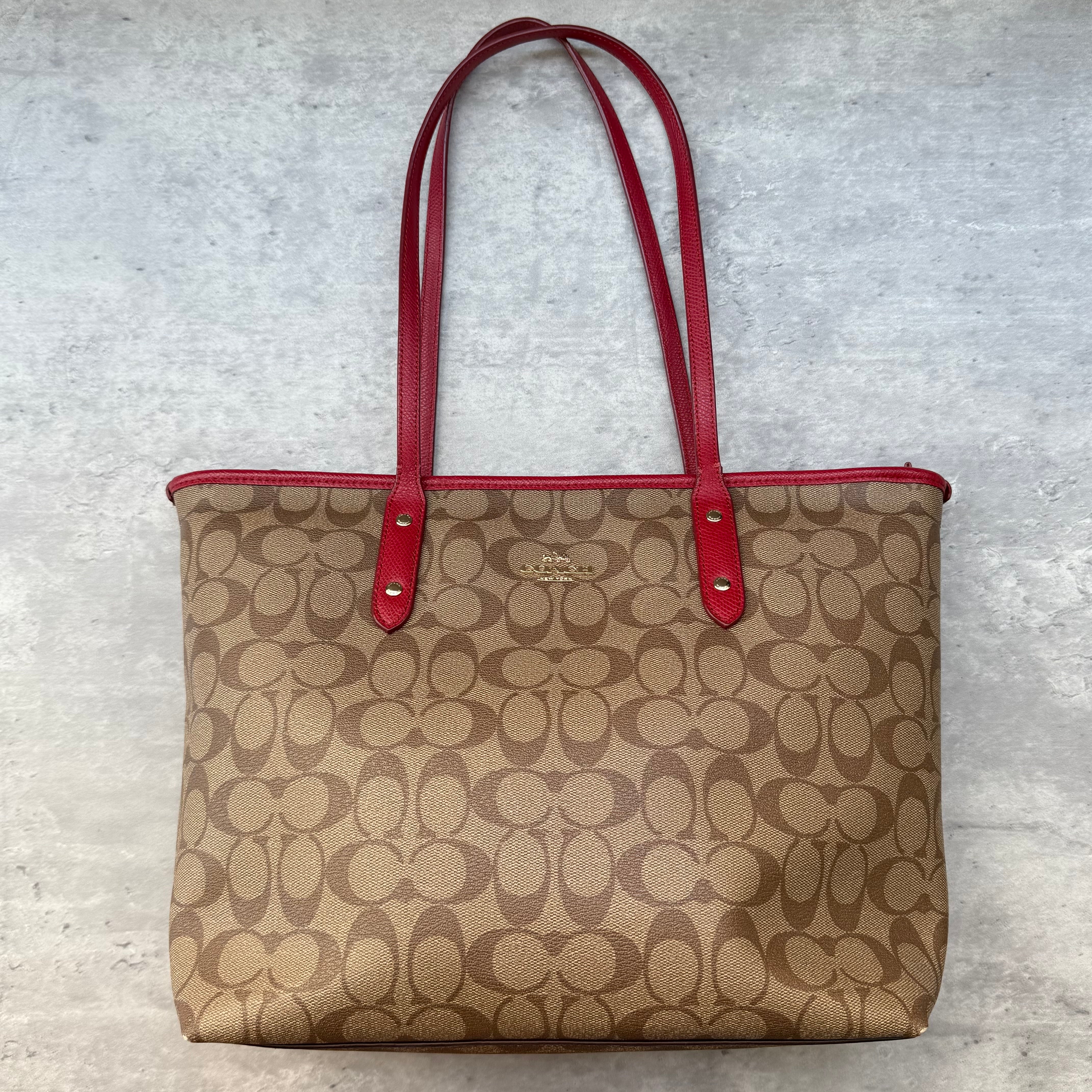 Coach Signature Canvas City Tote Bag in beige monogram canvas with red leather trims and gold-tone hardware, featuring spacious interior and zip closure.