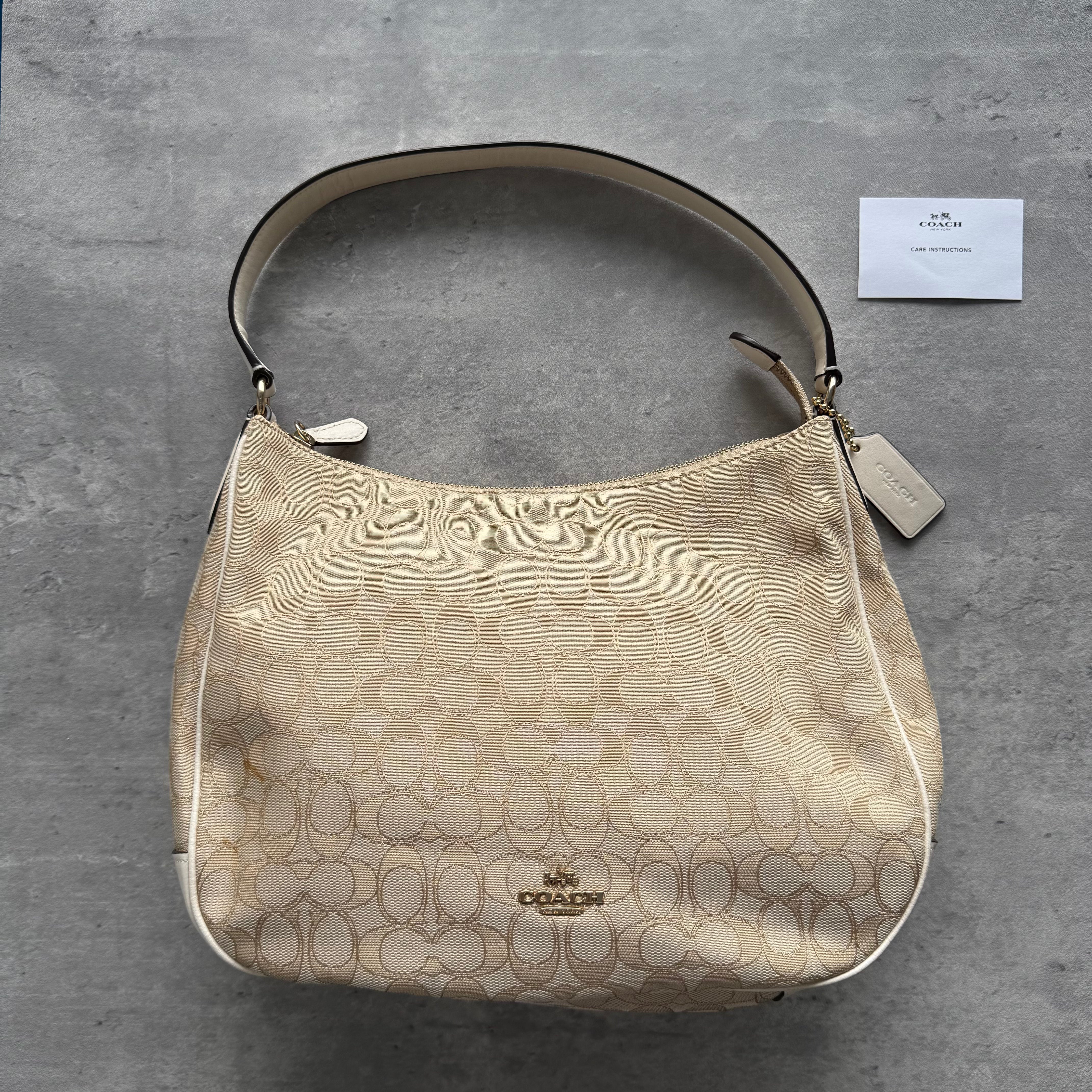Coach Signature Canvas Hobo Shoulder Bag in beige and white, crafted from jacquard canvas with leather trim and gold-tone hardware.