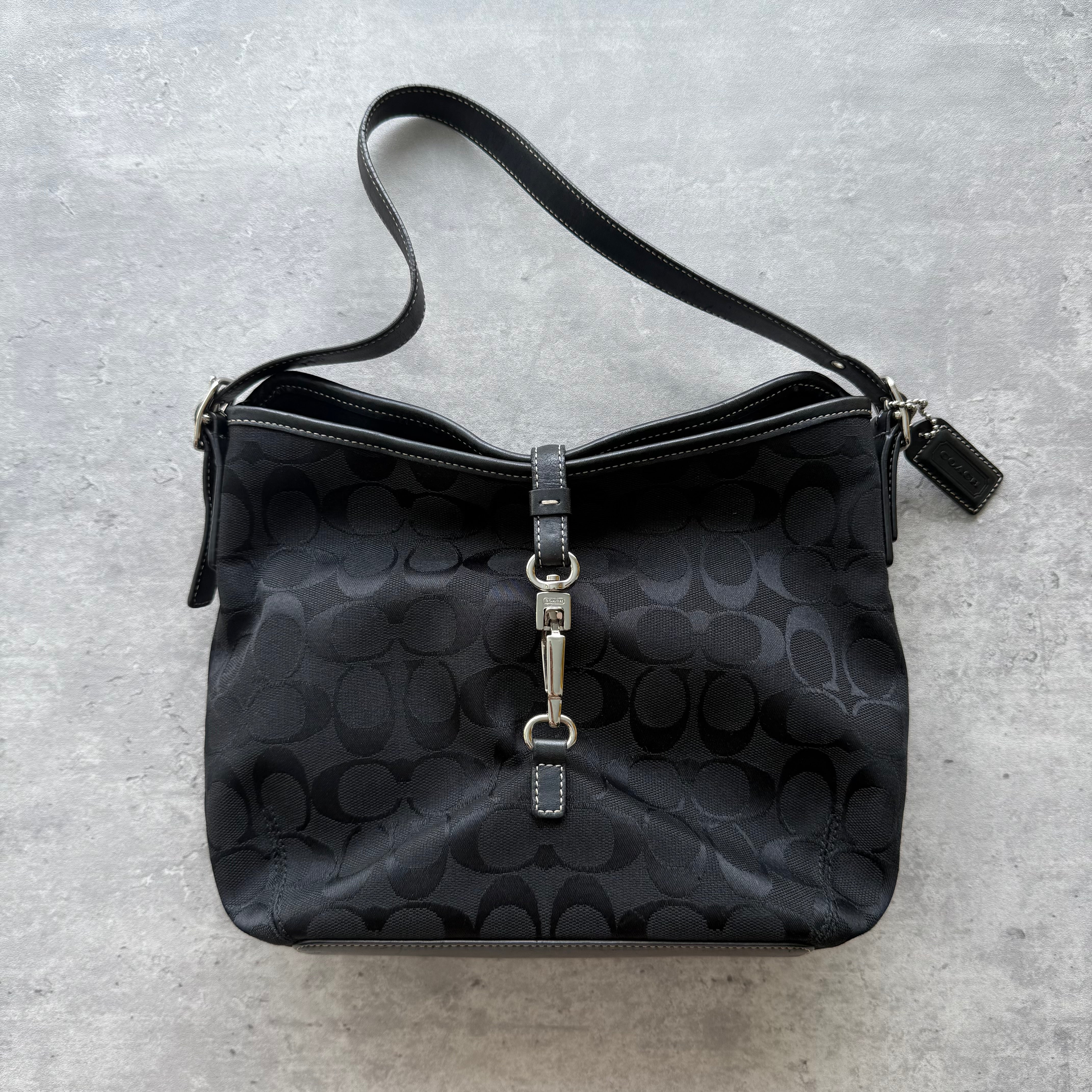 Coach Signature Clip Shoulder Bag in black jacquard with tonal monogram, leather trim, and silver-tone clip closure.