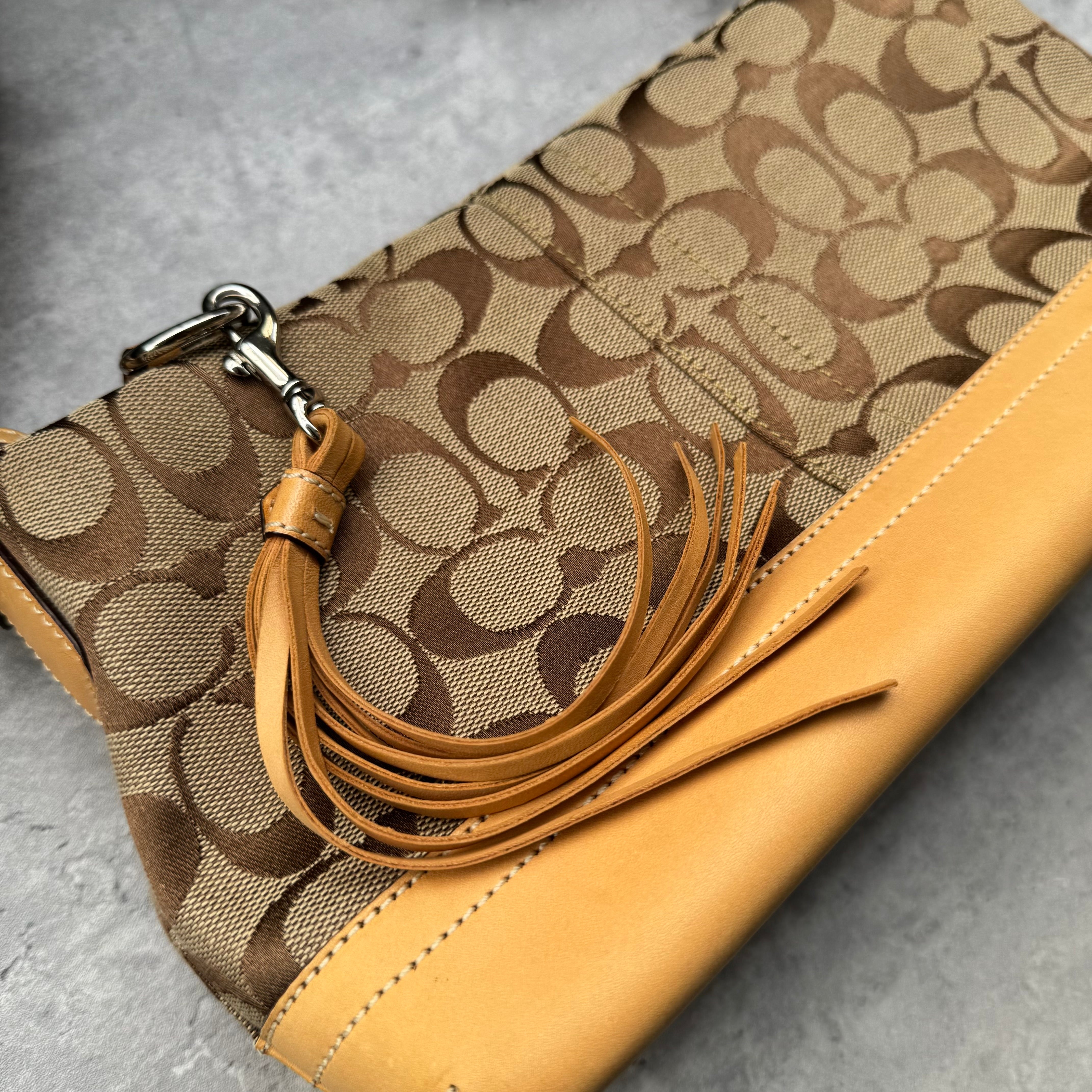 Coach Signature Coated Canvas Tassel Shoulder Bag in brown monogram print with tan leather trim and tassel detail.