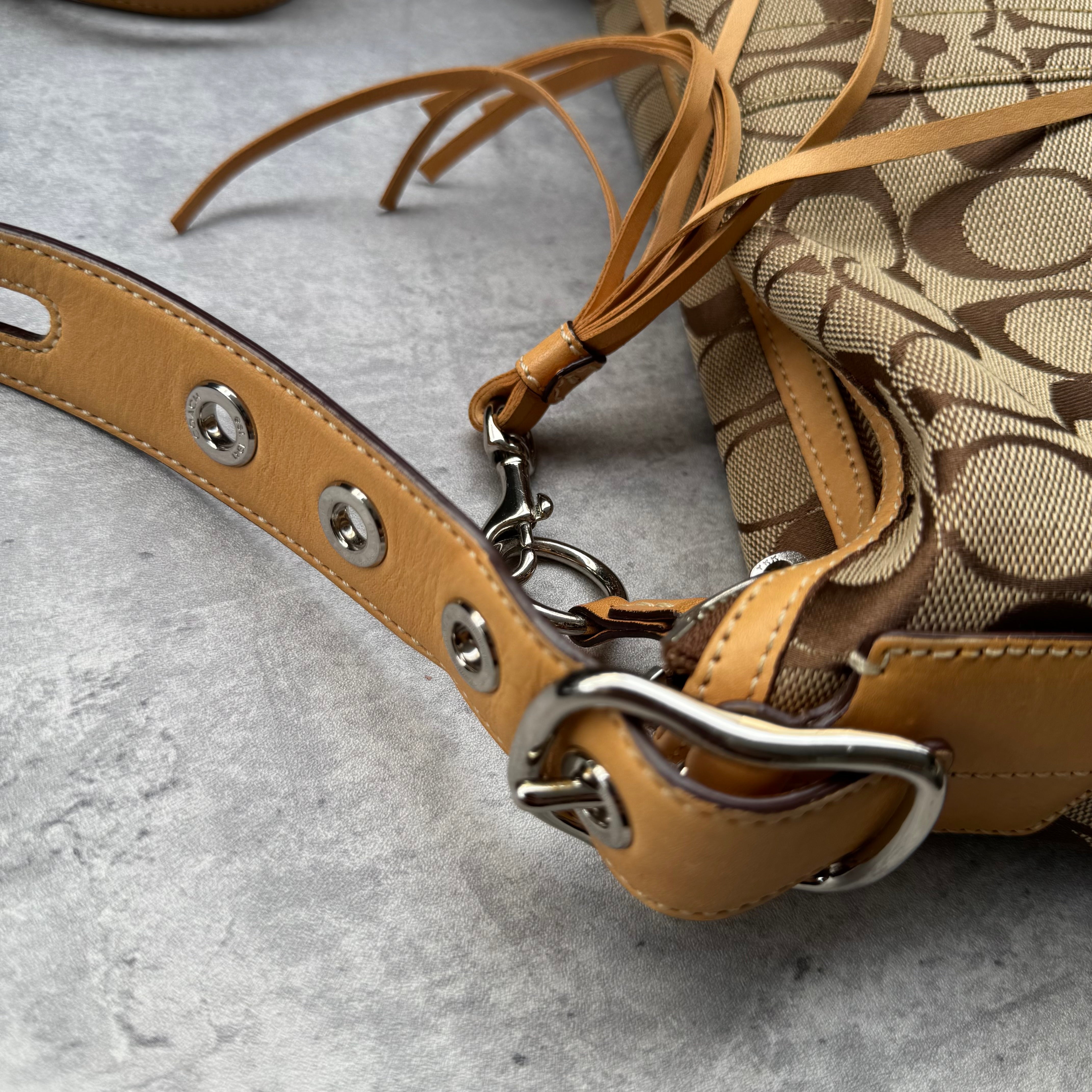 Coach Signature Coated Canvas Tassel Shoulder Bag in brown monogram print with tan leather trim and tassel detail.