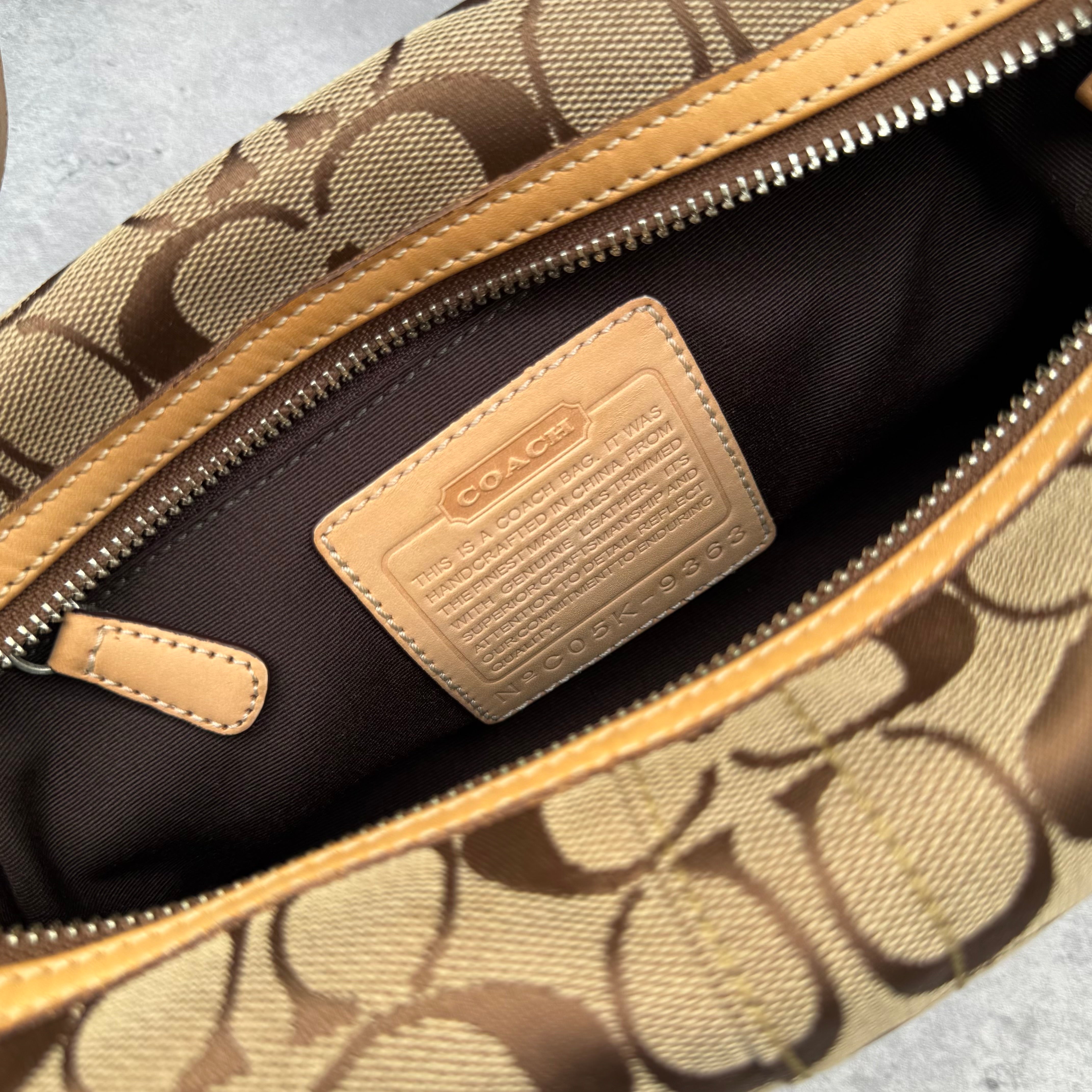 Coach Signature Coated Canvas Tassel Shoulder Bag in brown monogram print with tan leather trim and tassel detail.