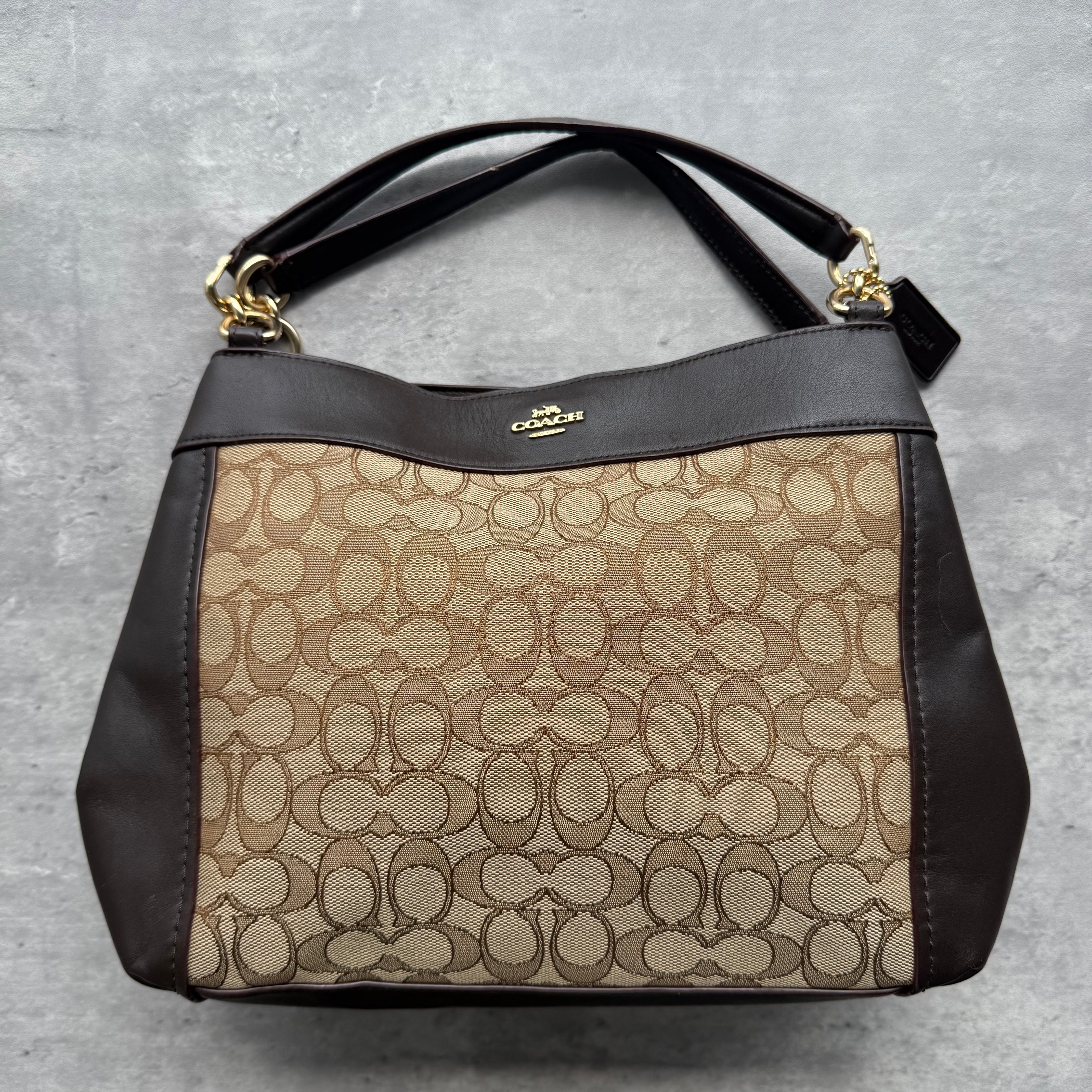 Coach Signature Lexy Canvas Shoulder Bag in beige and brown with jacquard canvas, leather trim, and gold-tone hardware.