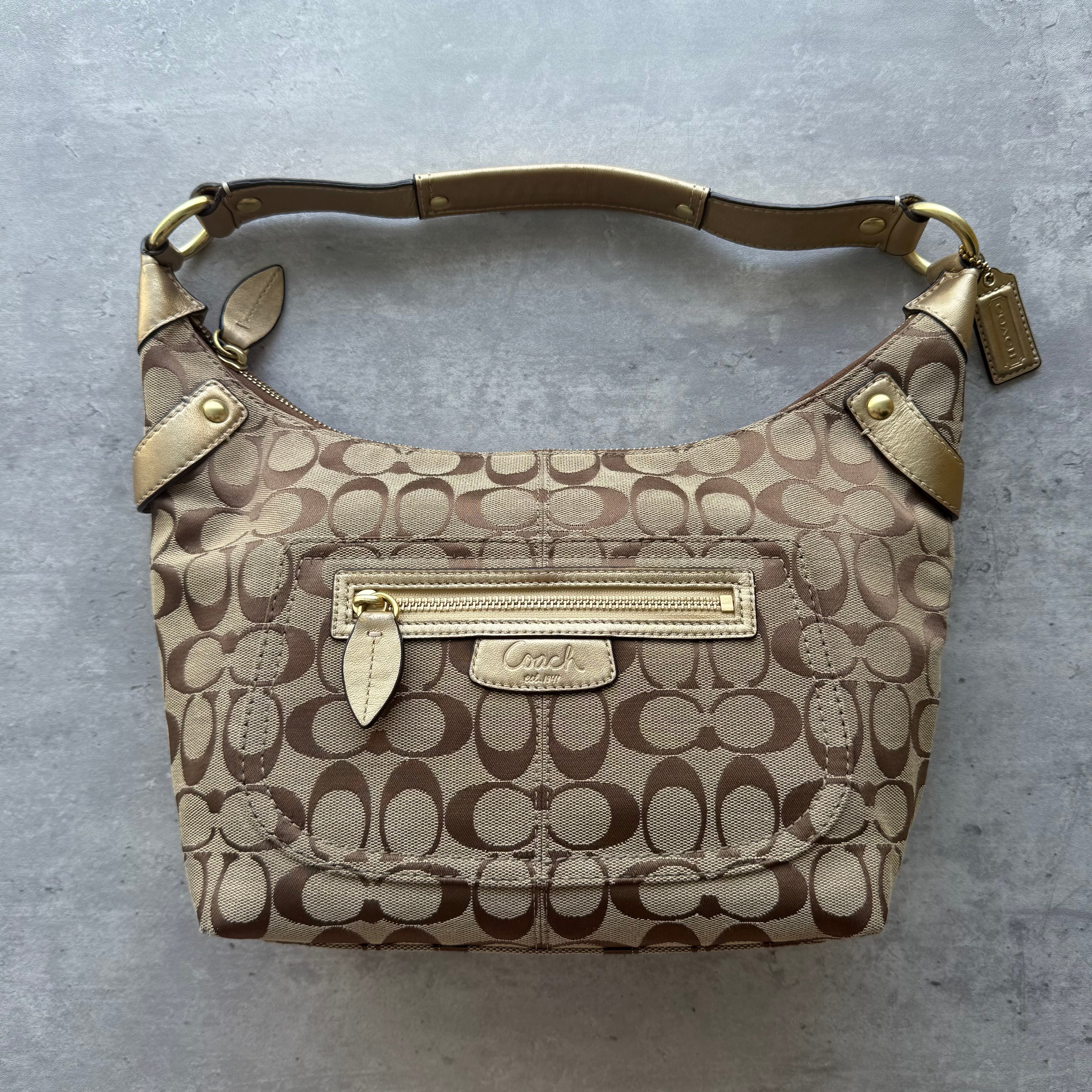Coach Signature Penelope Shoulder Bag in beige jacquard with gold leather trim, gold-tone hardware, and front zip pocket.