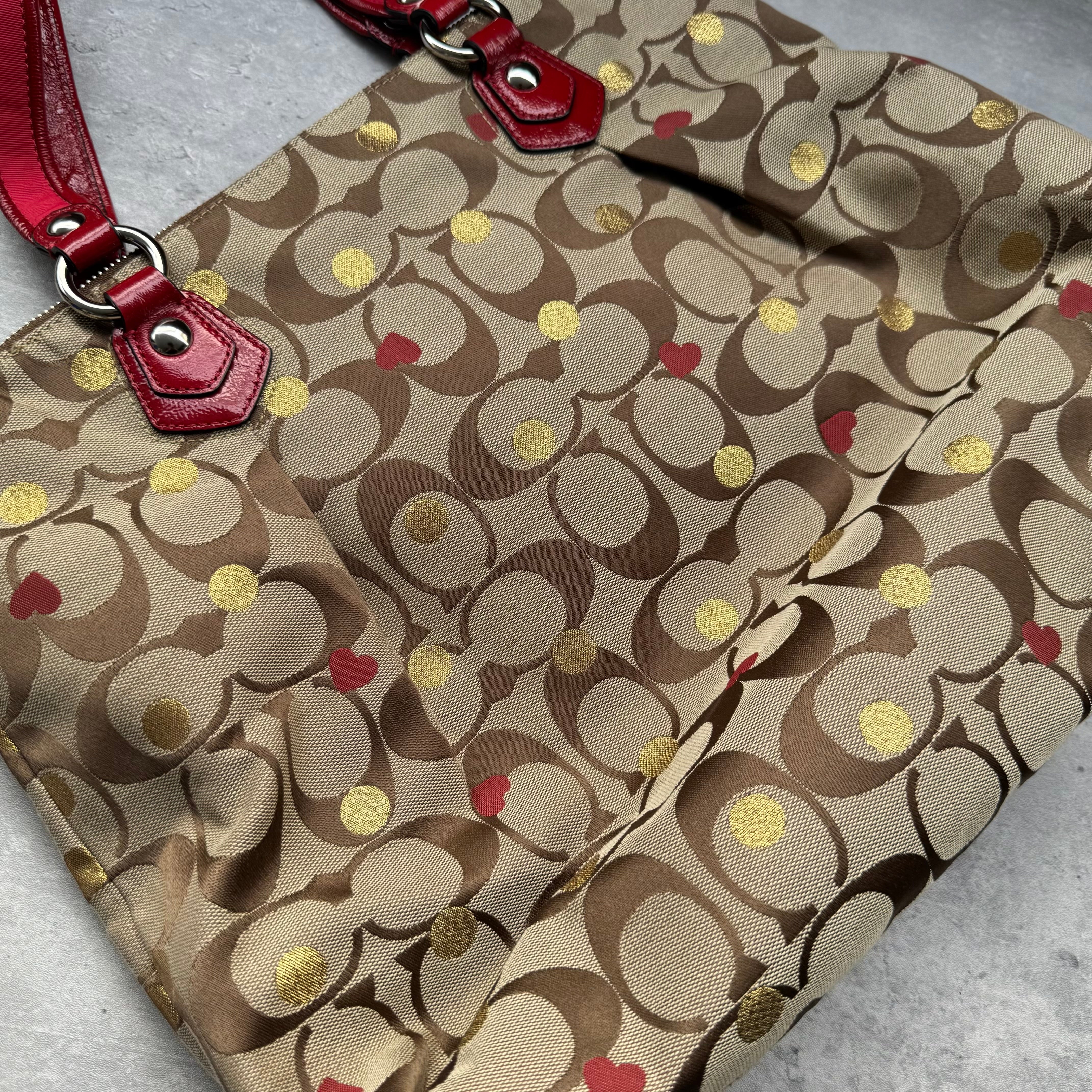 Coach Signature Poppy Laura Secret Admirer Tote Bag in brown monogram canvas with red and gold heart dot accents and red patent leather trim.