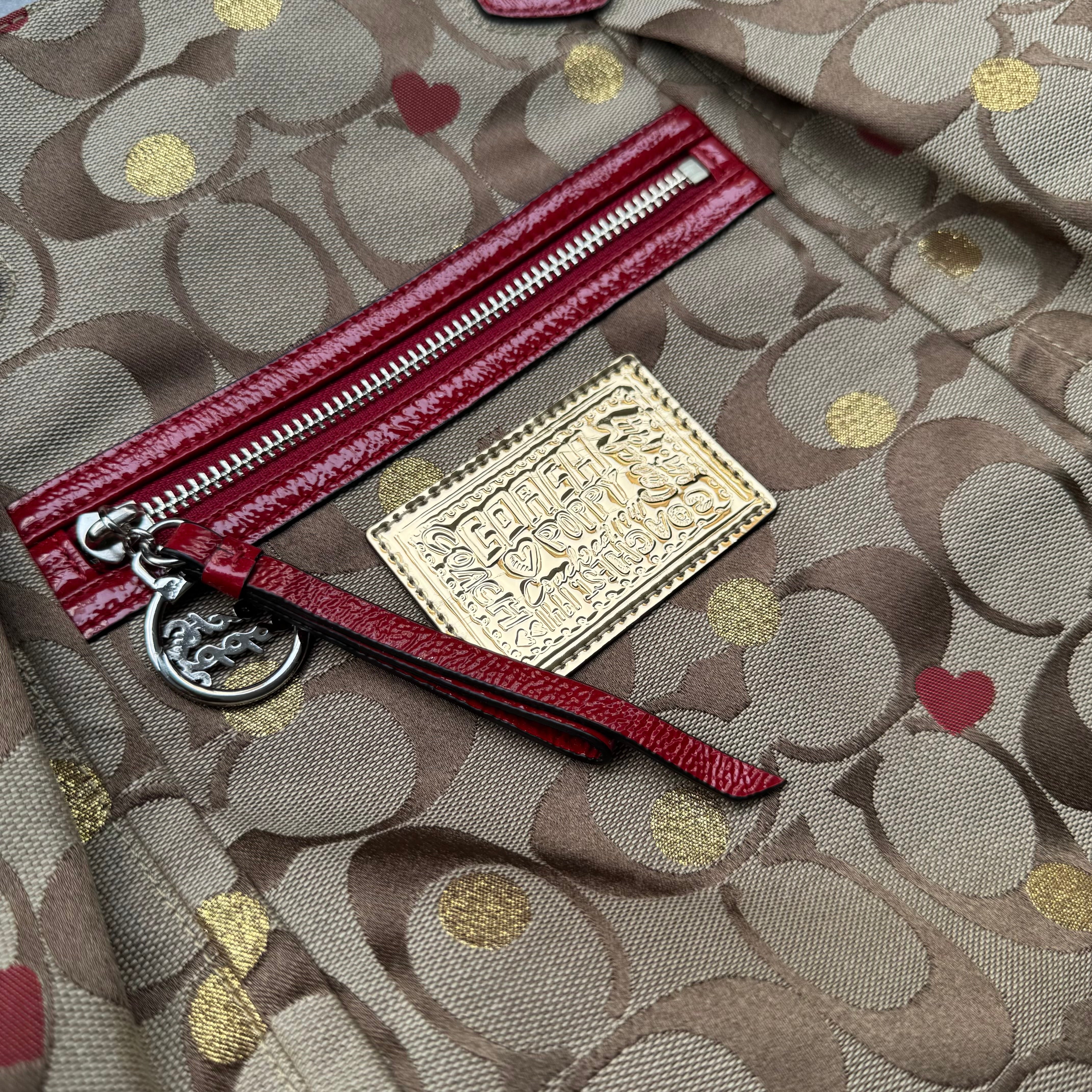 Coach Signature Poppy Laura Secret Admirer Tote Bag in brown monogram canvas with red and gold heart dot accents and red patent leather trim.