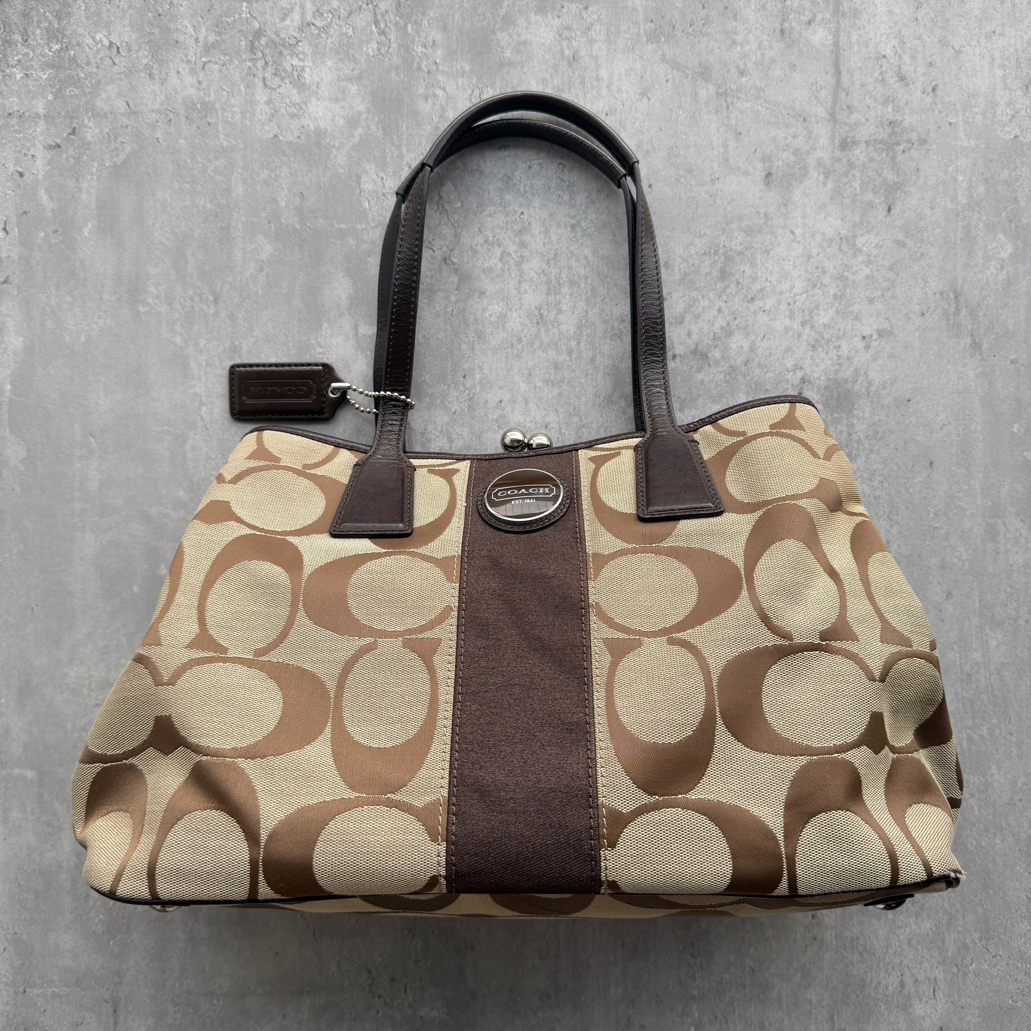Coach Signature Stripe Kisslock Tote Bag in brown and beige canvas with leather trim and kisslock compartment.