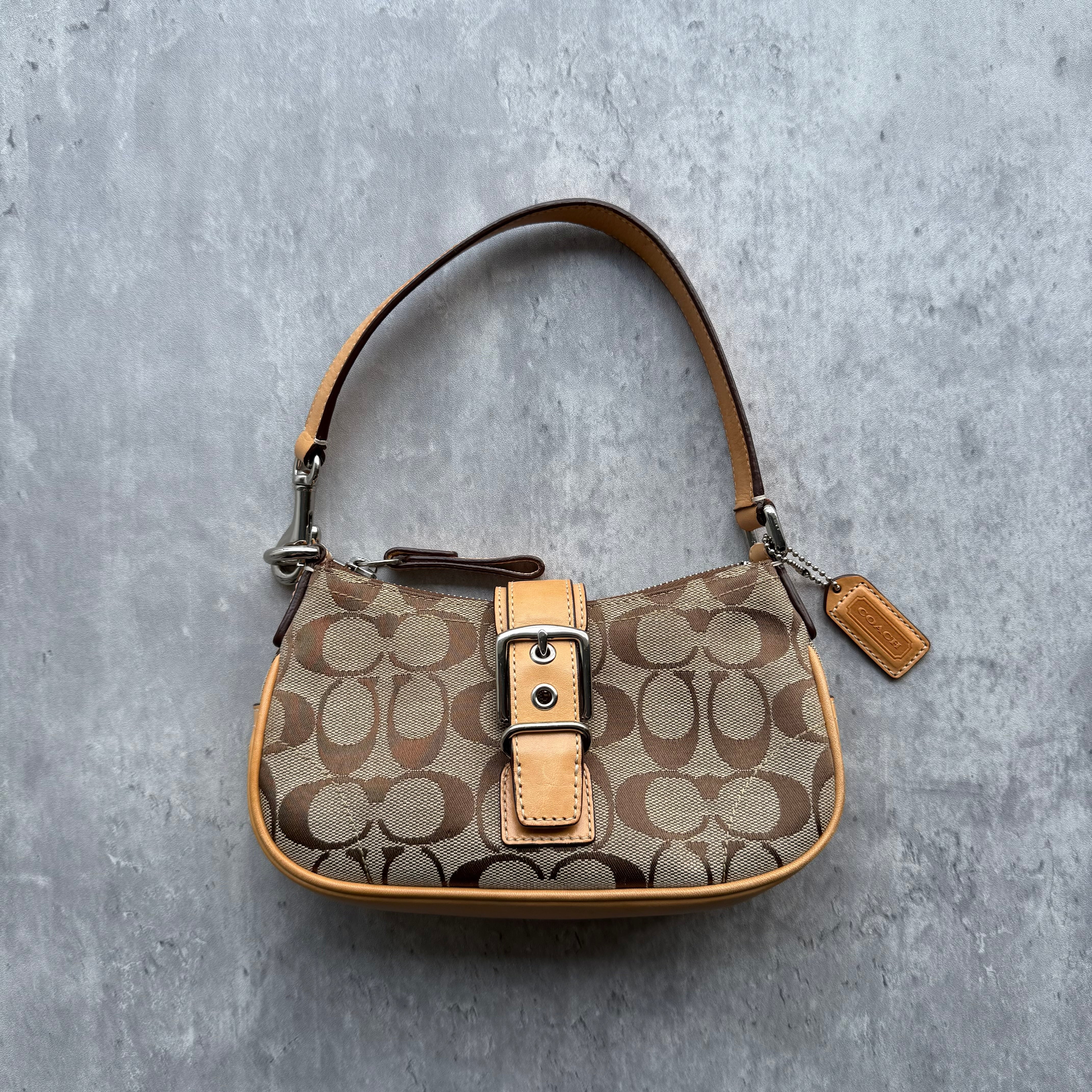 Coach Signature Tabby Shoulder Bag in beige monogram canvas with tan leather buckle tab, silver hardware, and orange interior lining.