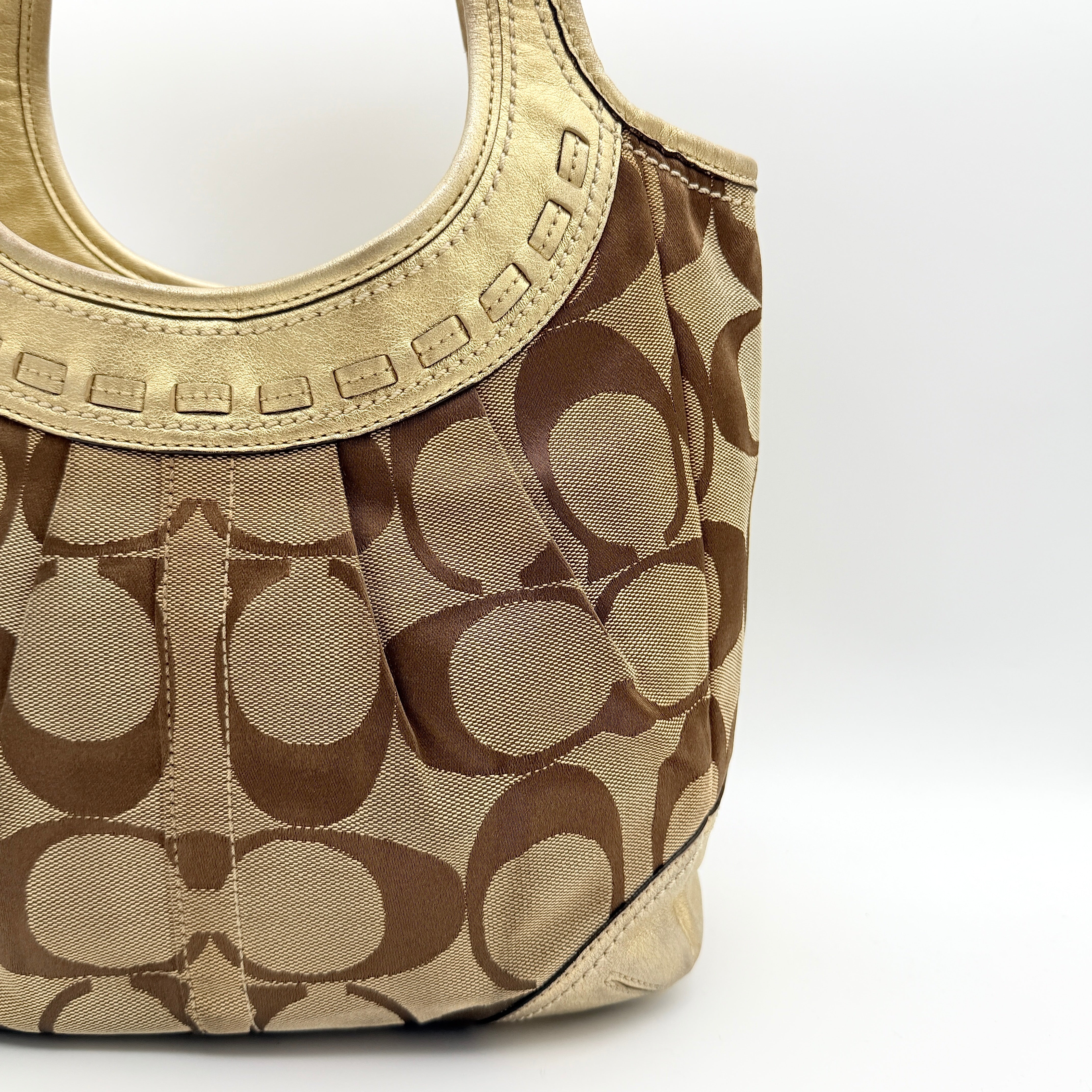 Coach Ergo Hobo Shoulder Bag in beige jacquard canvas with gold leather trim, shown standing upright against a white background.