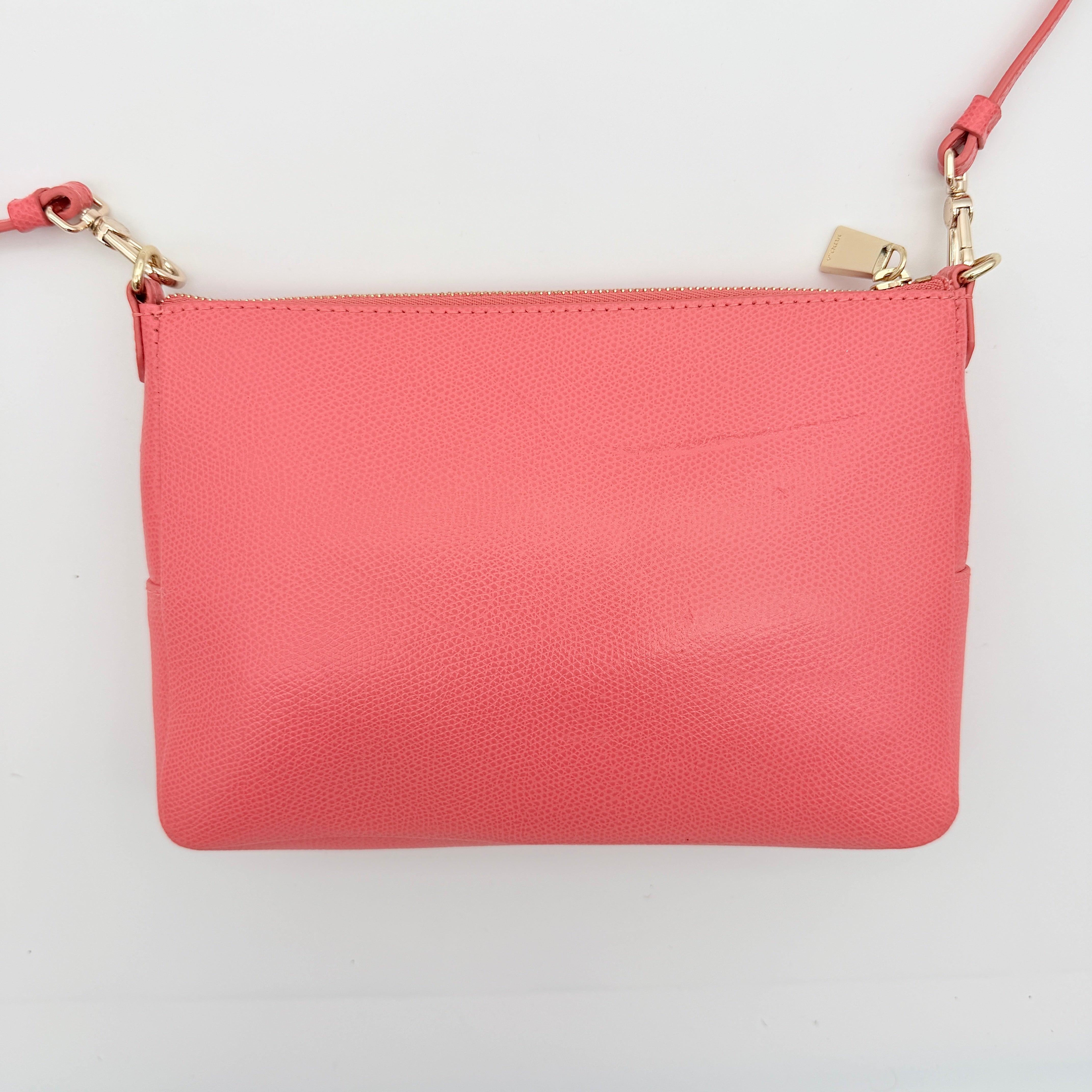 Furla pink leather crossbody bag with gold zip and adjustable strap, photographed flat on a white background.