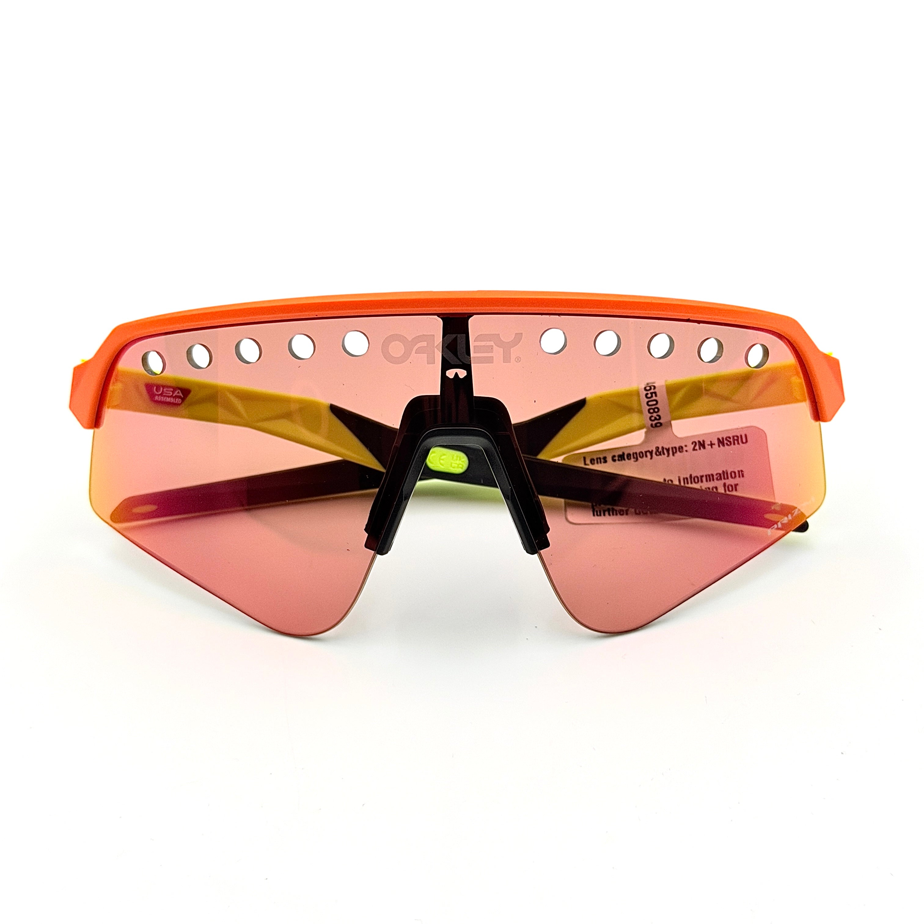 Oakley Sutro Lite Sweep sunglasses in neon yellow and orange with Prizm Trail Torch shield lens, displayed with box and case.