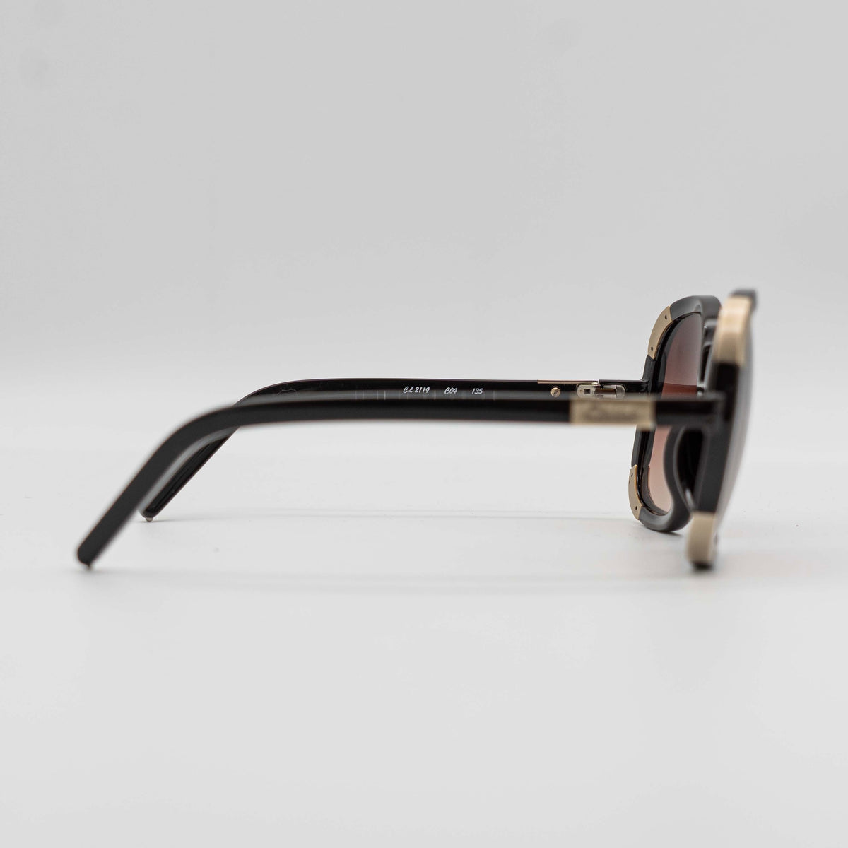 Chloé CL2119 sunglasses in black with gold-tone accents and brown gradient lenses, displayed at an angle.