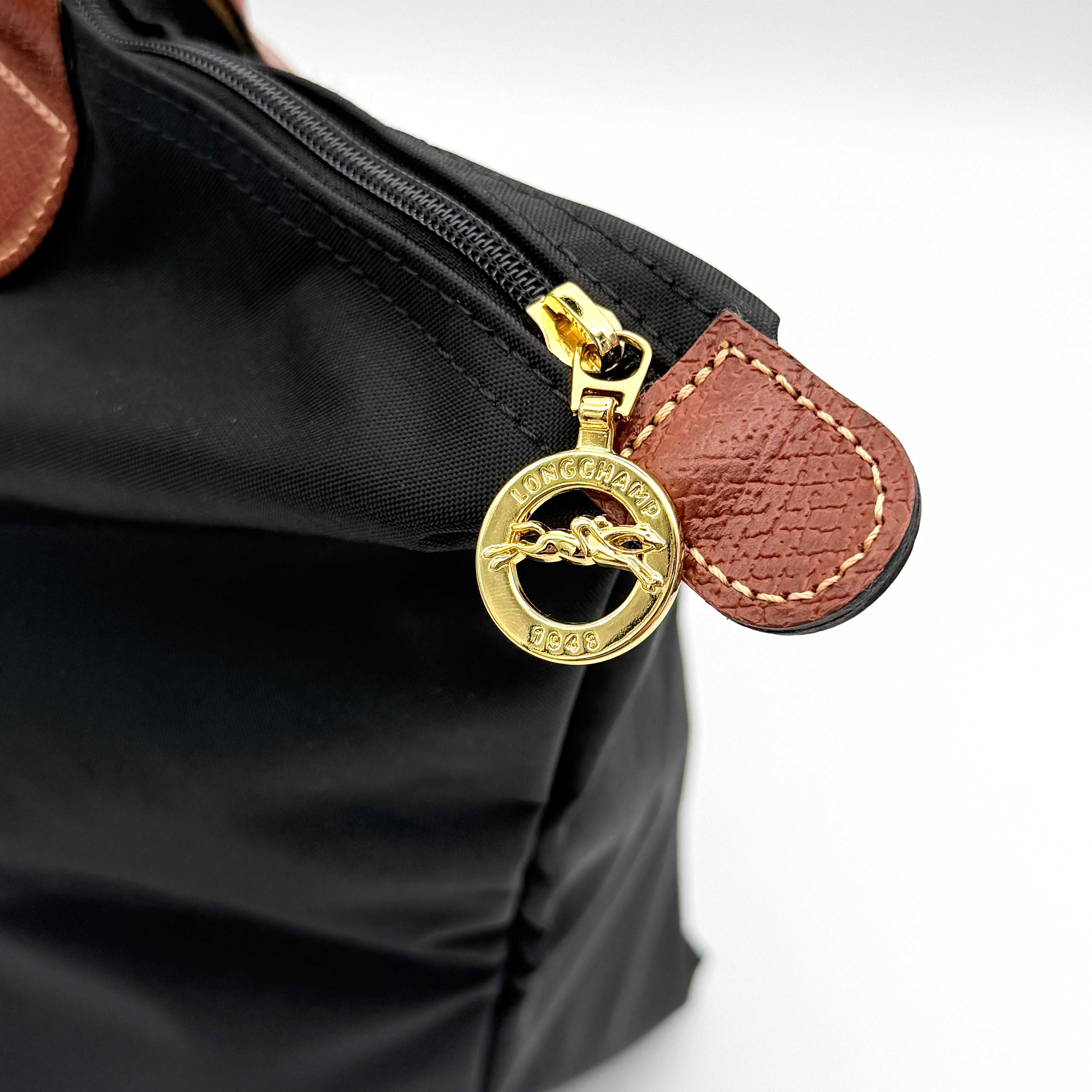 Longchamp Le Pliage Original Tote Bag in black with brown leather handles and flap, photographed against a white background.