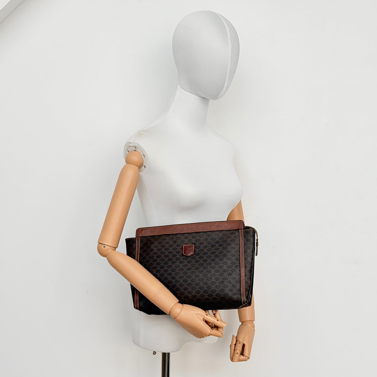 Celine Triomphe Macadam Clutch Bag in brown coated canvas with leather trim, photographed on a white background.