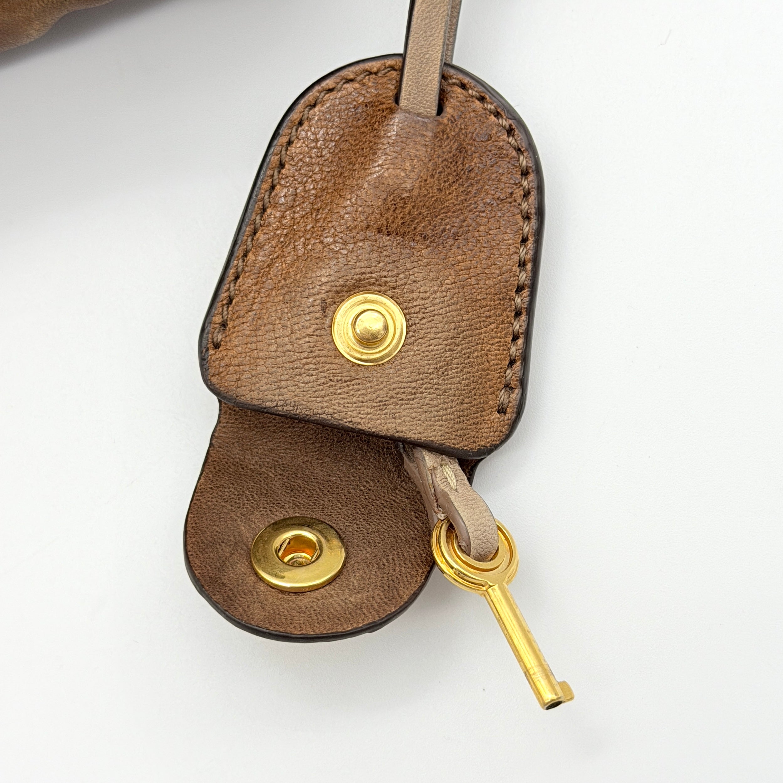 Miu Miu brown Matelasse Coffer Hobo bag with gold hardware, detachable strap, and dust bag displayed on a flat surface.