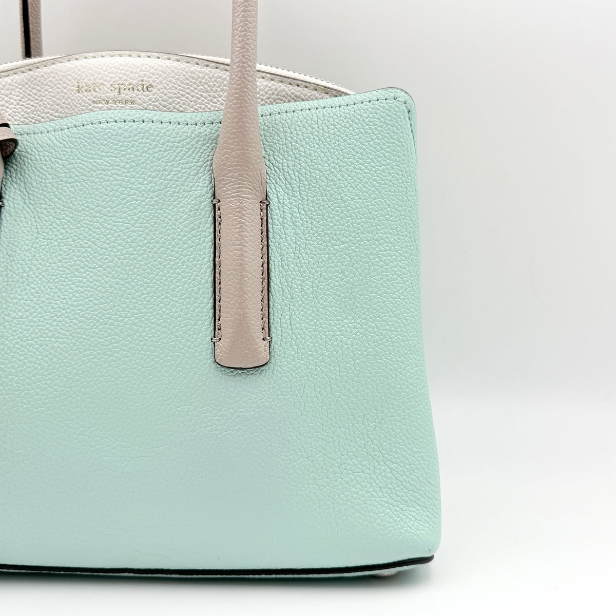 Kate Spade New York Margaux satchel in mint green pebbled leather with taupe handles, shown with its detachable strap and a clear pouch.