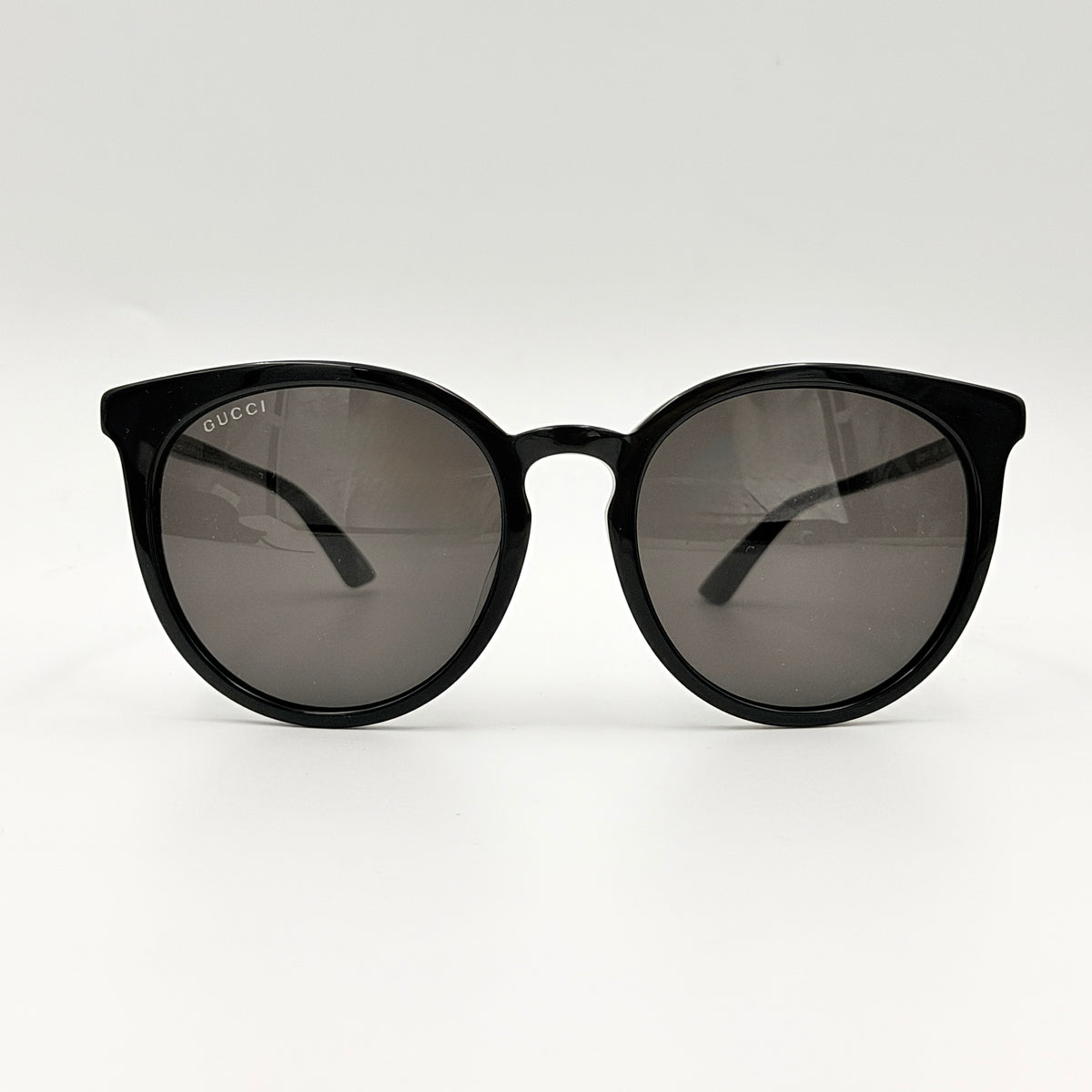 Gucci GG0064SK 001 black round sunglasses with smoky lenses, shown with original burgundy velvet case and pouch.